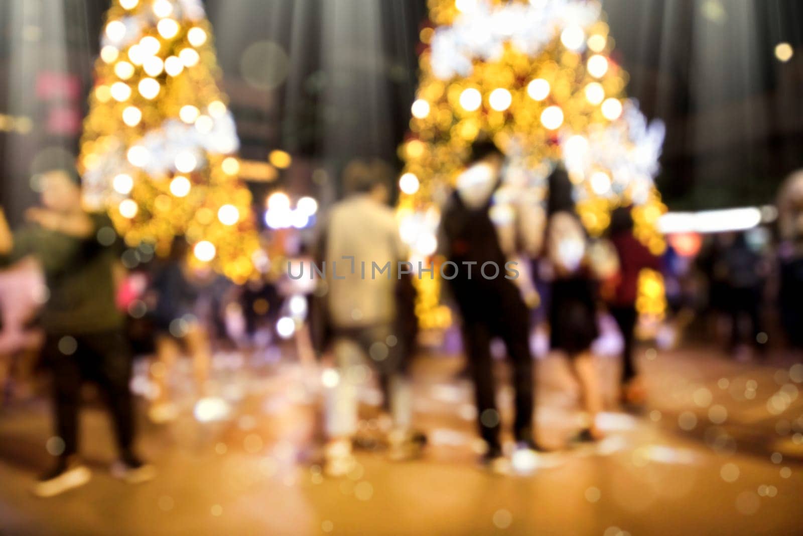Conceptual defocused Christmas decoration and crowd of people on city street at night