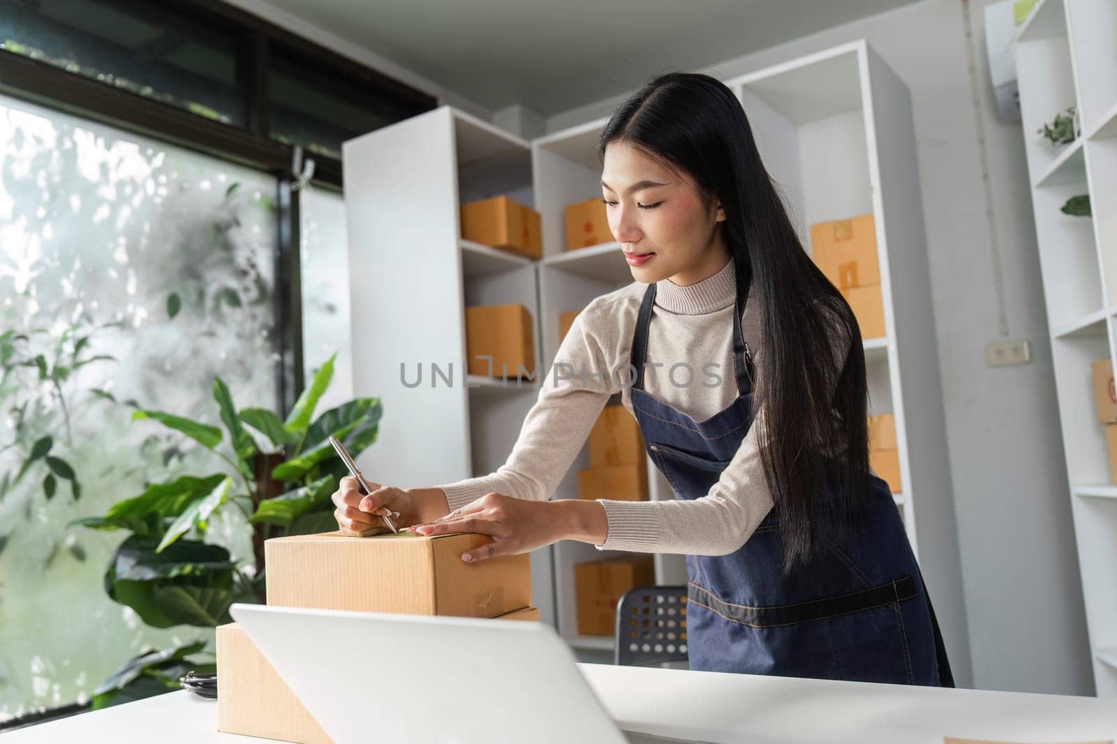A professional woman labels packages while managing inventory in a contemporary office, reflecting her organizational skills and dedication.