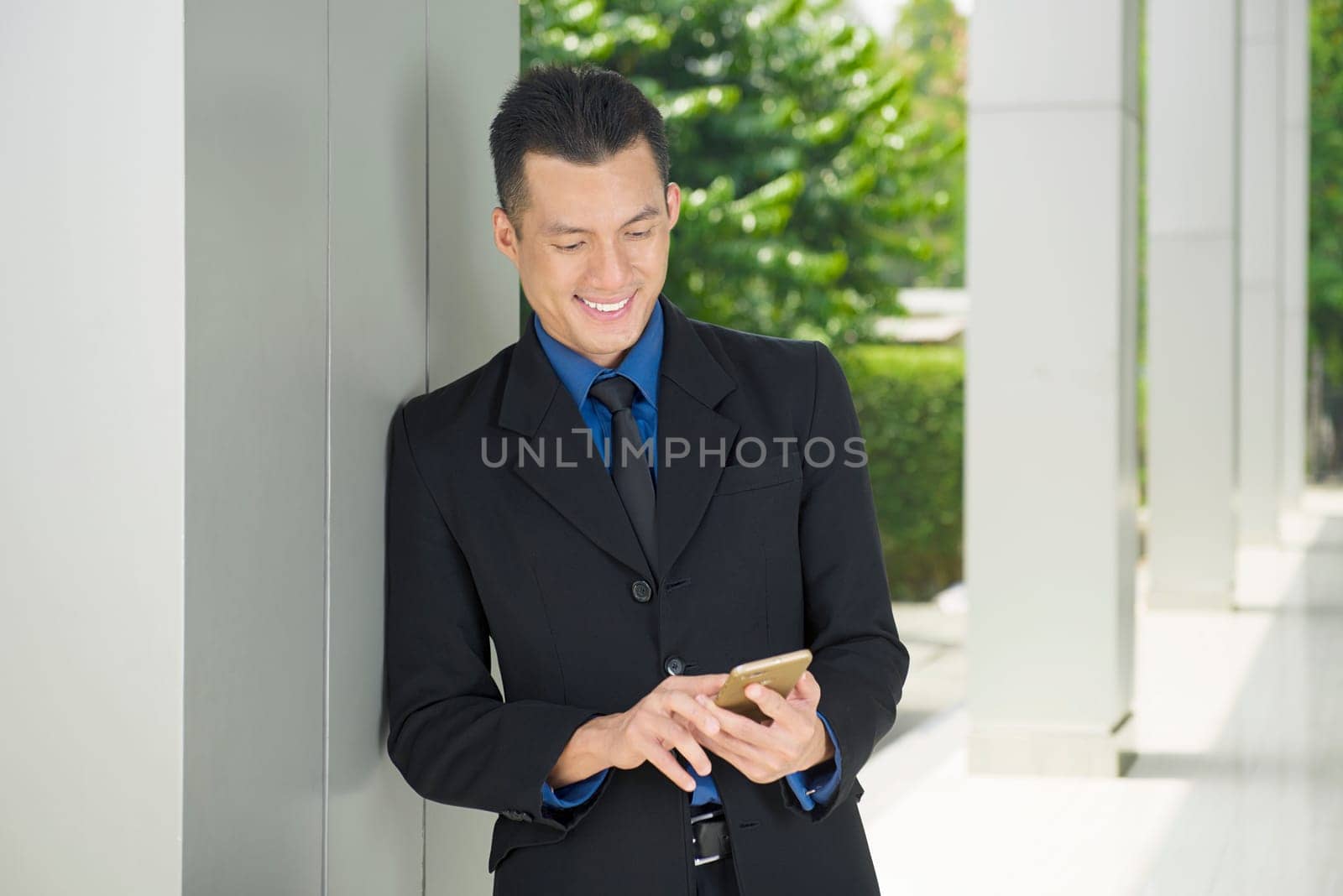 Young asian businessman using smartphone with relax outside office room