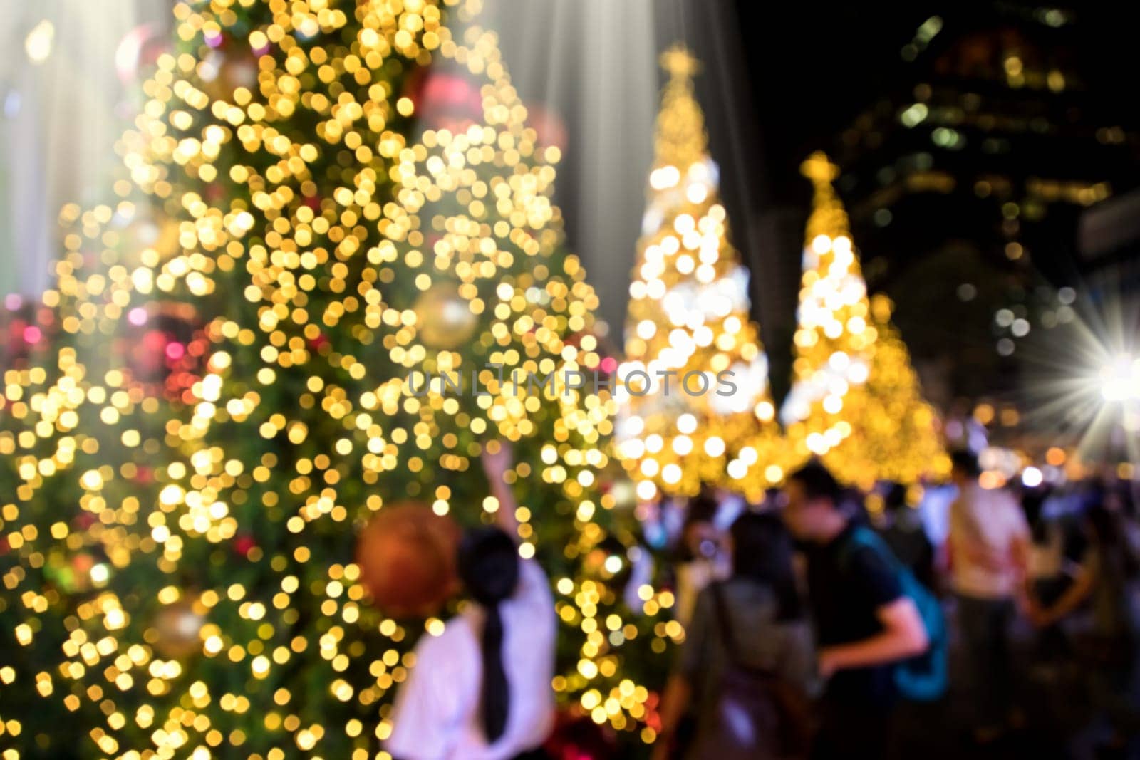 Conceptual defocused abstract decorated Christmas Tree and crowd of people on city street at night