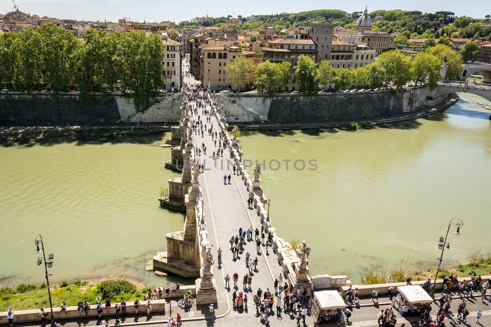 Rome, Italy, April 17th 2017: people walking on the Sant'Angelo bridge along the River Tiber in Rome. The bridge was built by Emperor Hadrian in 134 to attach to the left bank of the river his mausoleum