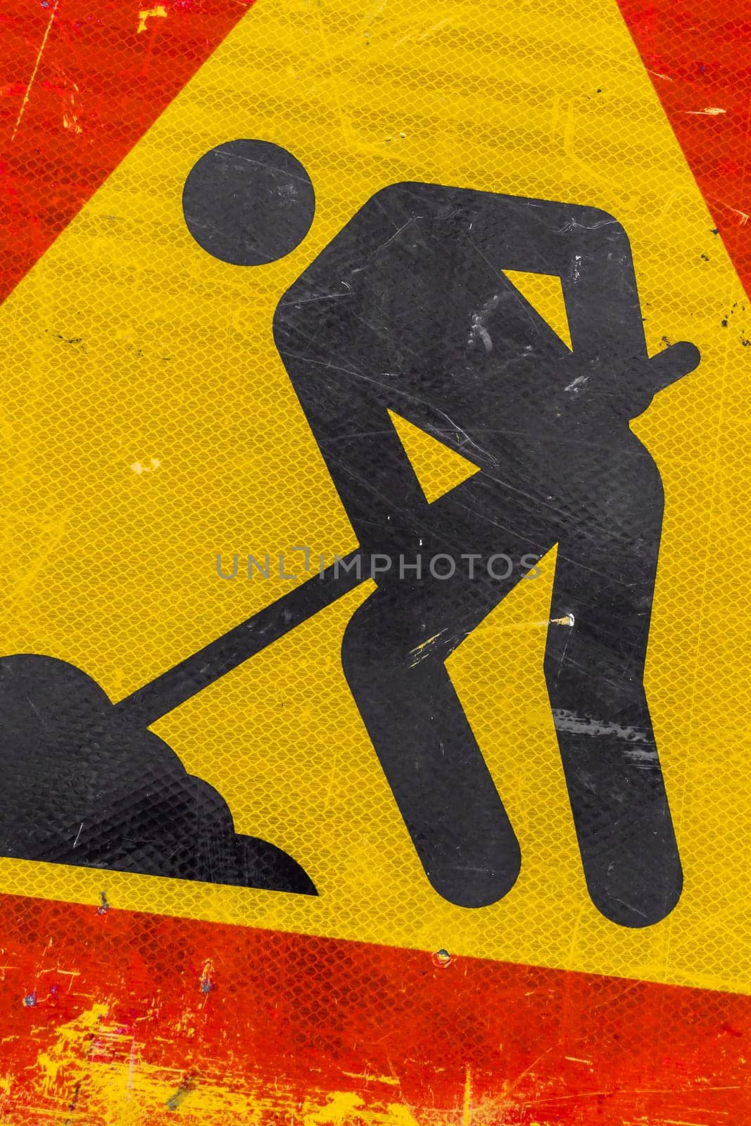 Close - up of road under construction traffic sign. Warning sign road repairing. Red, black and yellow triangle road sign work.
