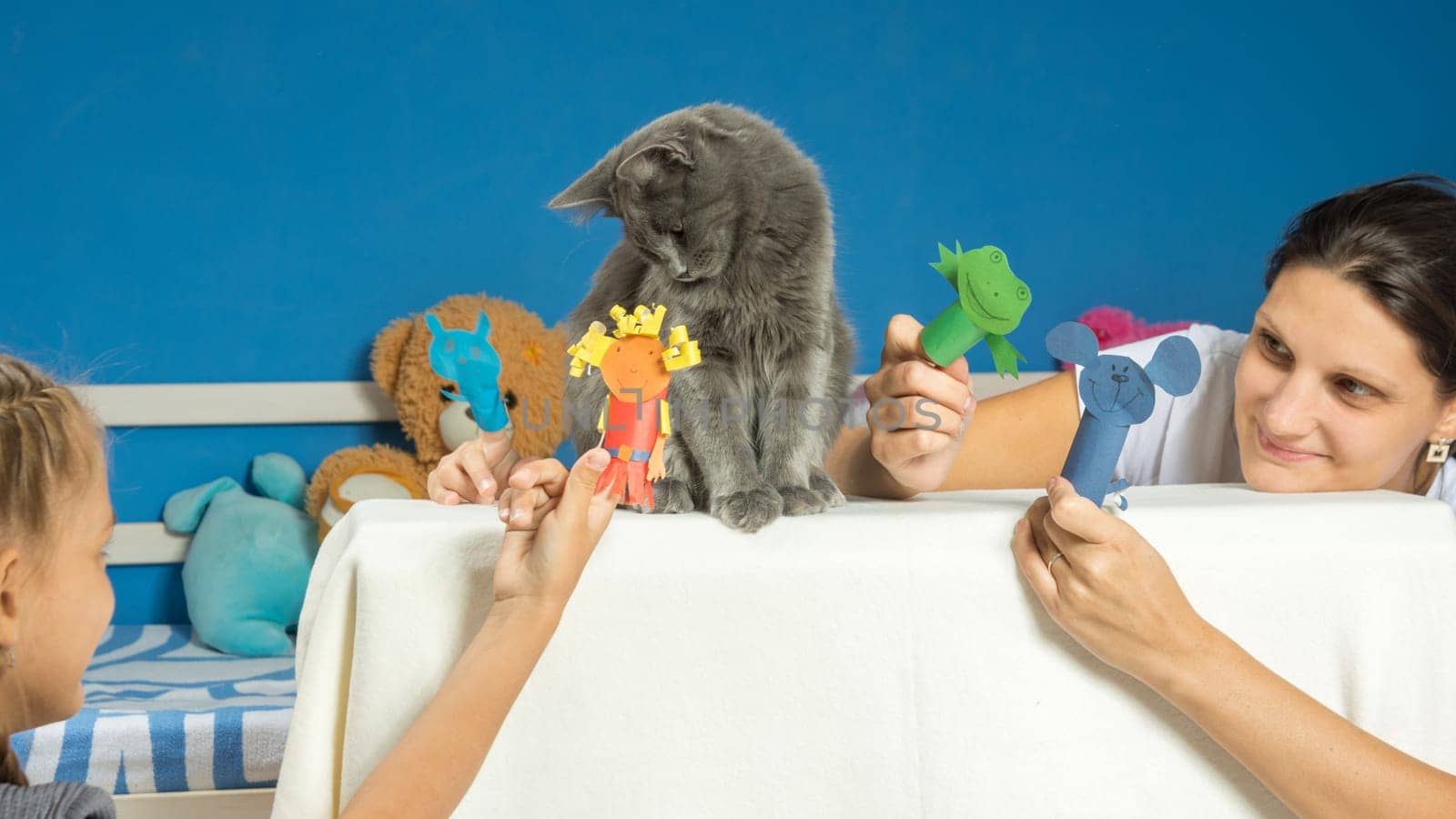 Mom and daughter play a puppet theater with a tired cat