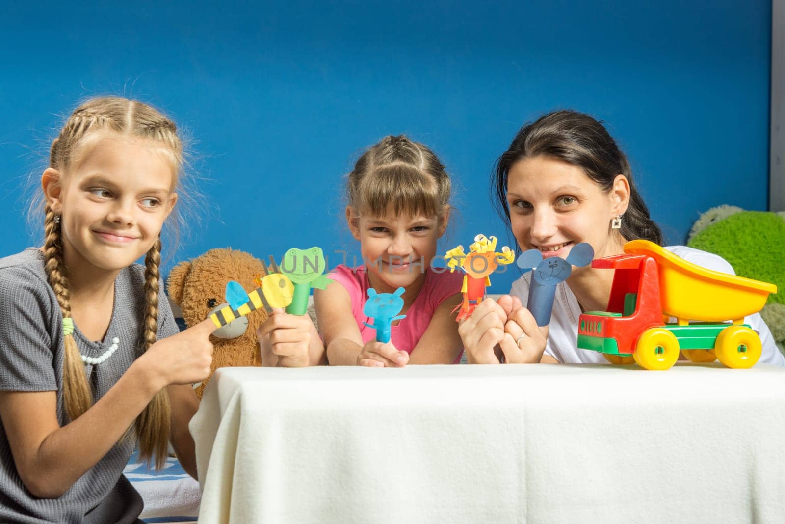 Mom with two daughters playing in a makeshift finger puppet theater