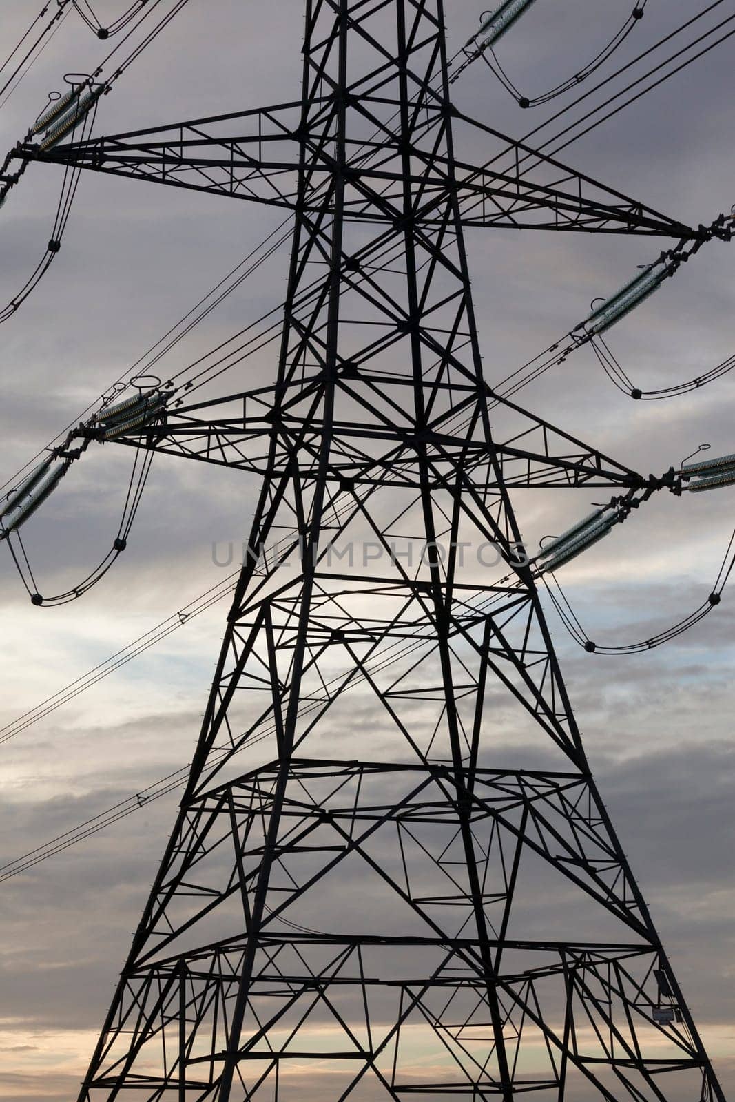 Electricity pylons or transmission towers carrying high voltage power lines and overhead cables above land as part of the national grid network supplying power to peoples homes and businesses