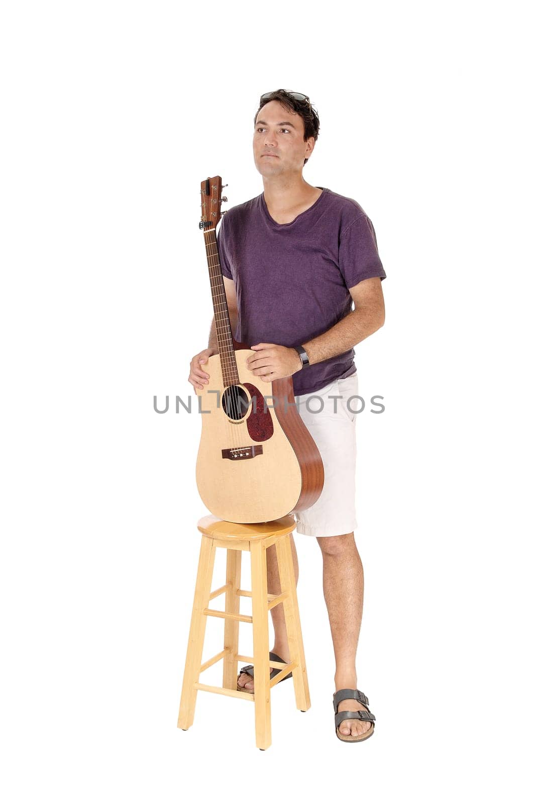 A handsome young man standing in a burgundy shirt holding his guitar,.looking away, isolated for white background.
