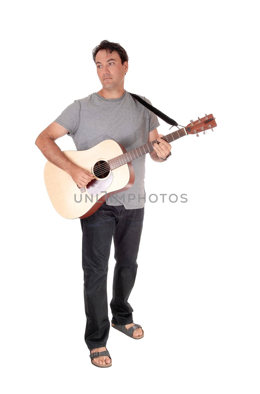 A young handsome man standing with his guitar and playing a song.in jeans and t-shirt, isolated for white background.