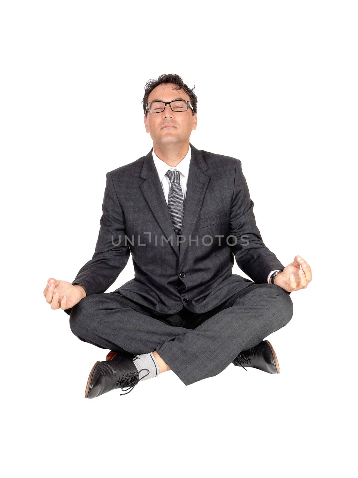 A handsome young man in a suit and tie sitting on the floor with eyes.closed and glasses meditation with yoga, isolate for white background.