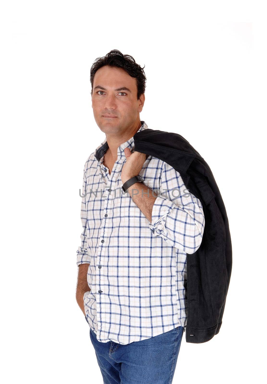 A tall handsome man standing in jeans with his black jacket over his.shoulder, looking into camera, isolated for white background.