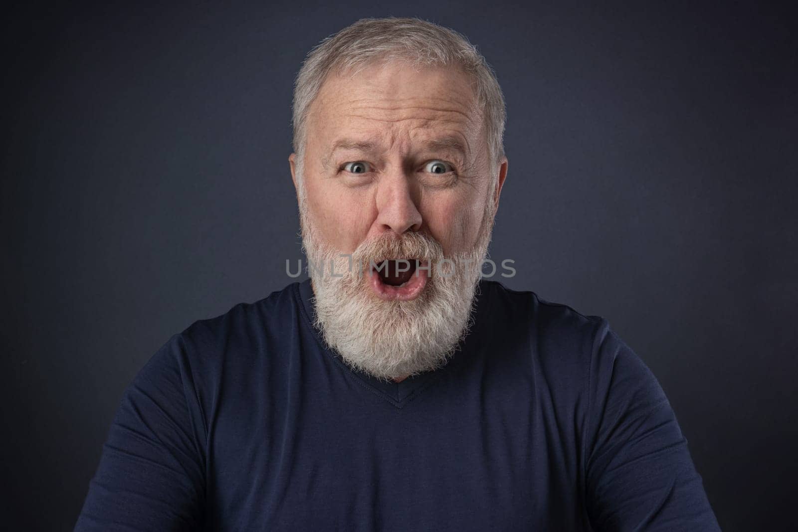An elderly man with a gray beard with a very surprised mimic