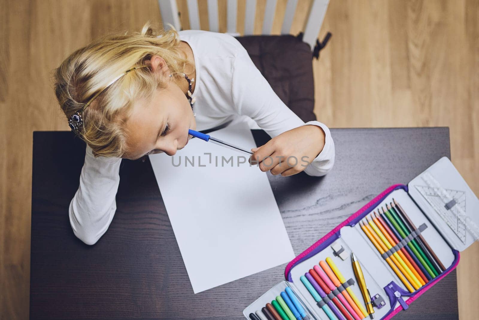 Cute girl comtemplation about her homework for elementary school at home.