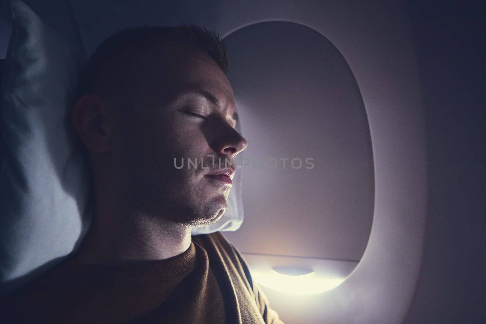 Traveling by airplane. Young passenger sleeping during flight.
