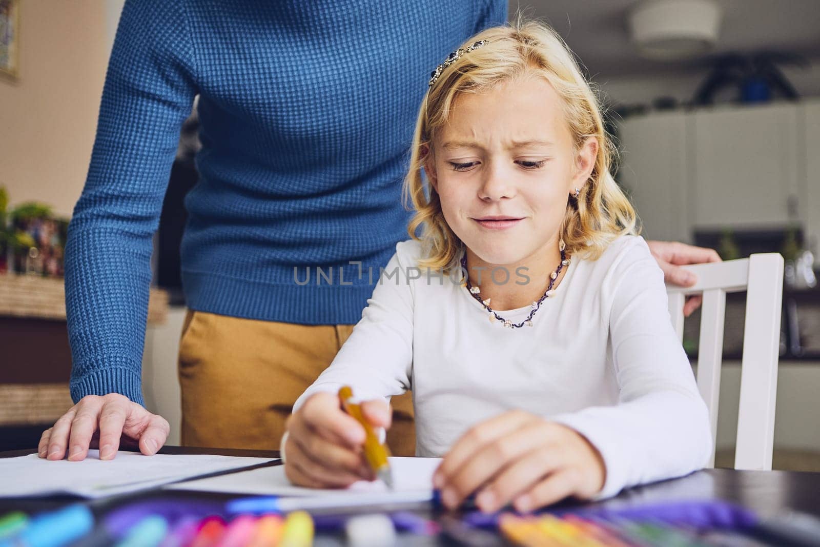 Father helping daughter with homework for elementary school at home.