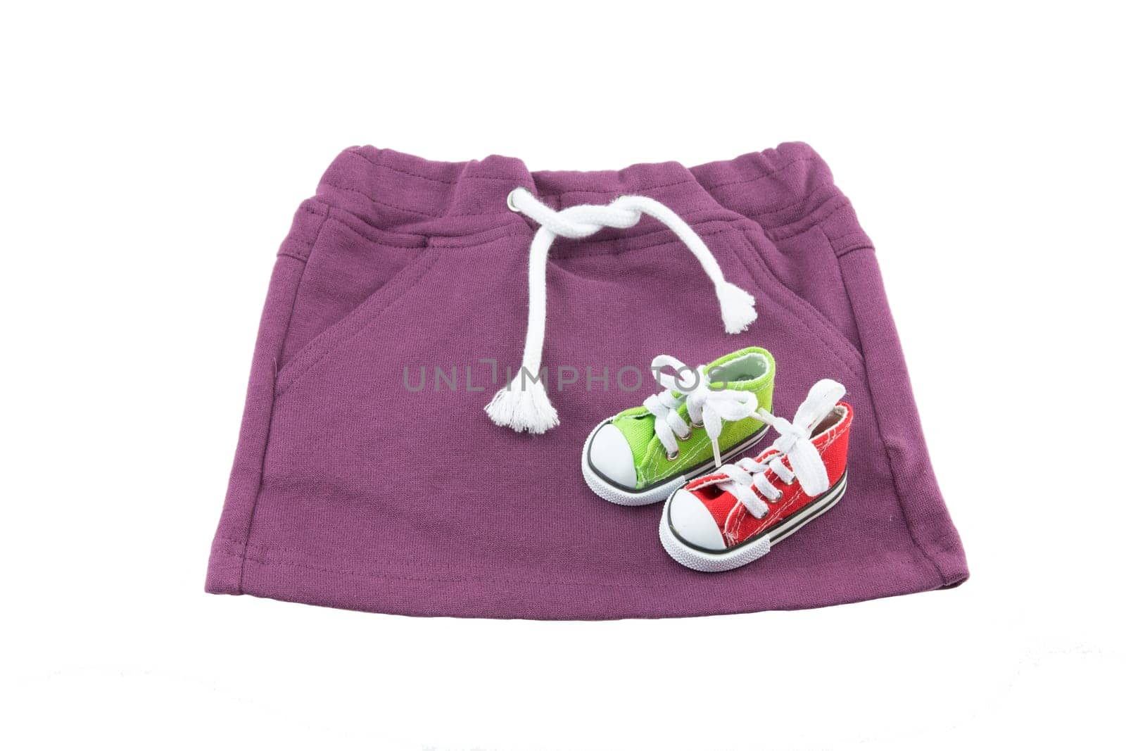 Baby clothes. purple skirt for baby with white linen twine isolated on a white background. Concept baby fashion. Decorated with mini sports shoes.
