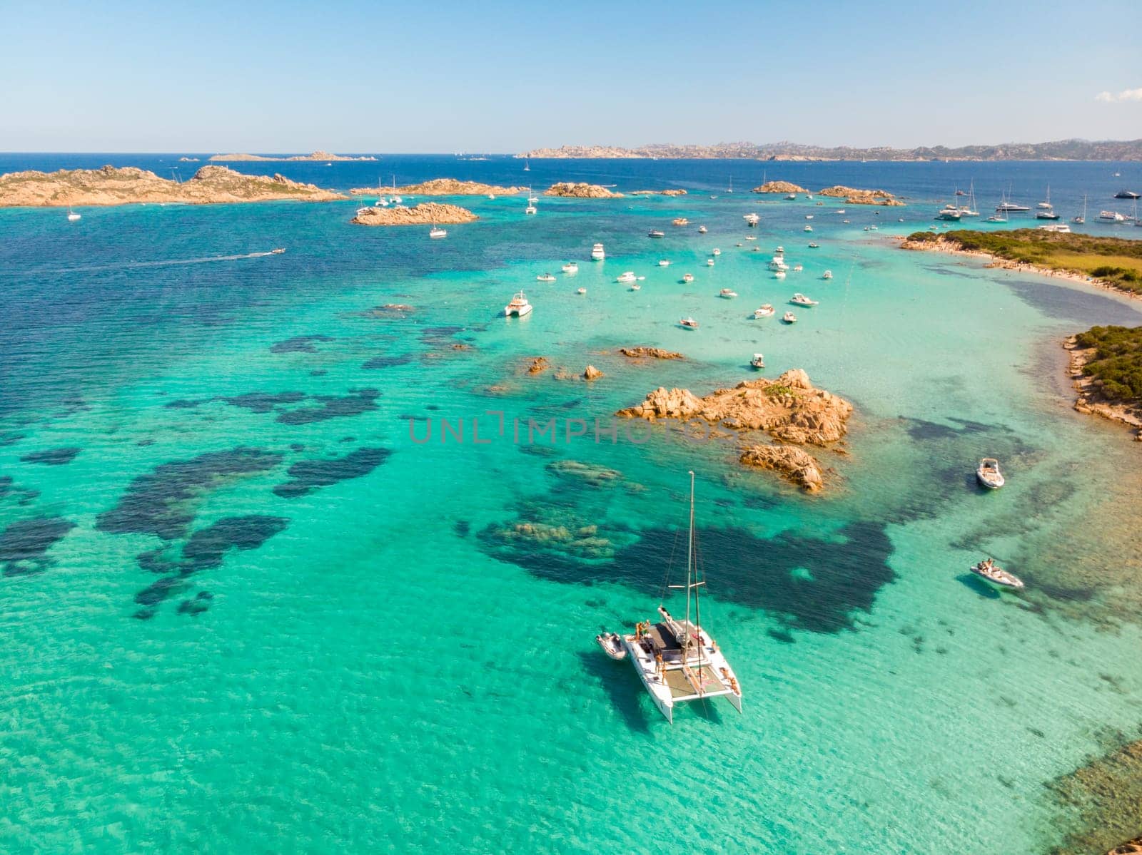 Drone aerial view of catamaran sailing boat in Maddalena Archipelago, Sardinia, Italy. Maddalena Archipelago is composed of Razzoli, Santa Maria and Budelli islands.