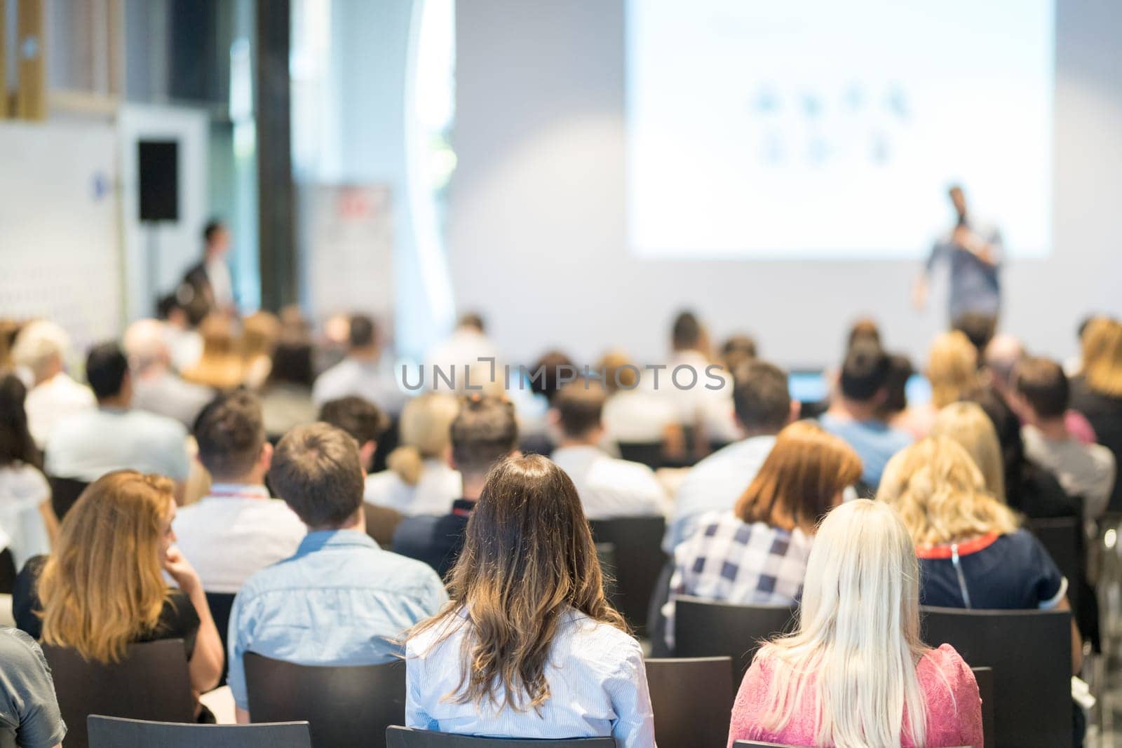 Speaker giving a talk in conference hall at business event. Audience at the conference hall. Business and Entrepreneurship concept. Focus on unrecognizable people in audience.