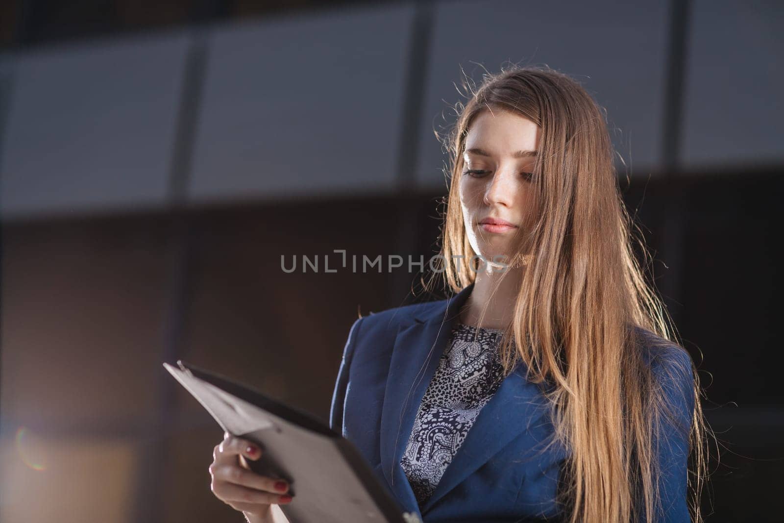 Successful businessman standing on background buildings looking at the folder charts of sales. City business woman working.