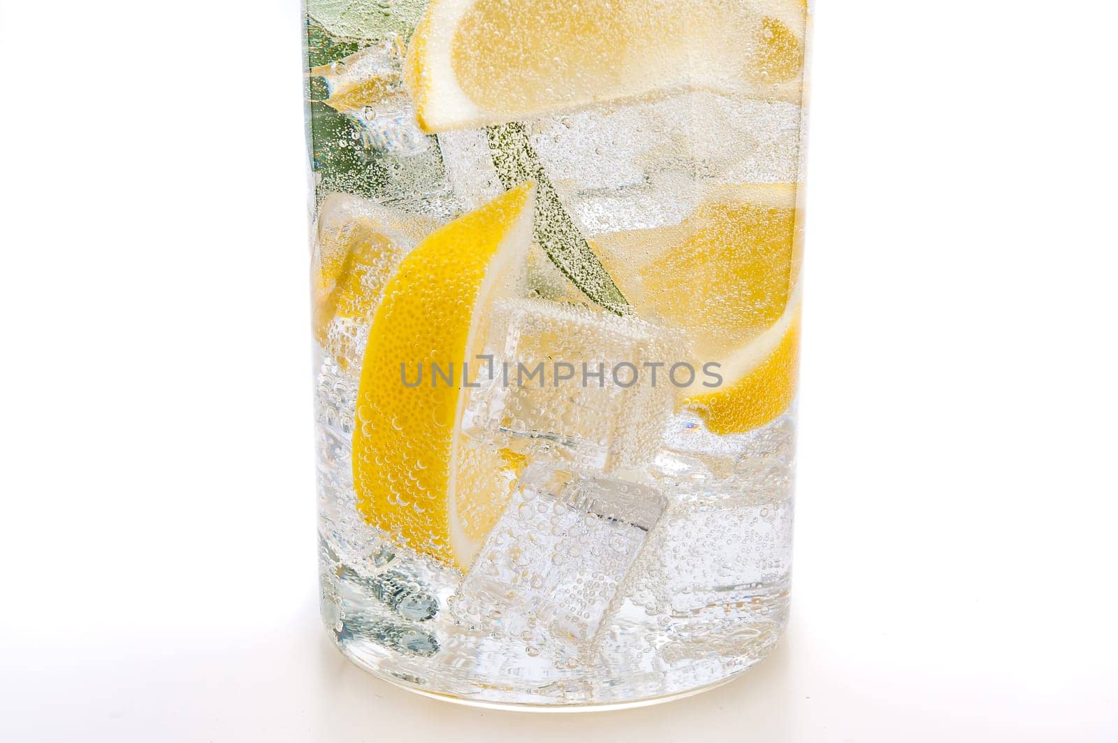 Drink of ice, the lobules of fresh juicy yellow lemon and crystal clear water in a glass.