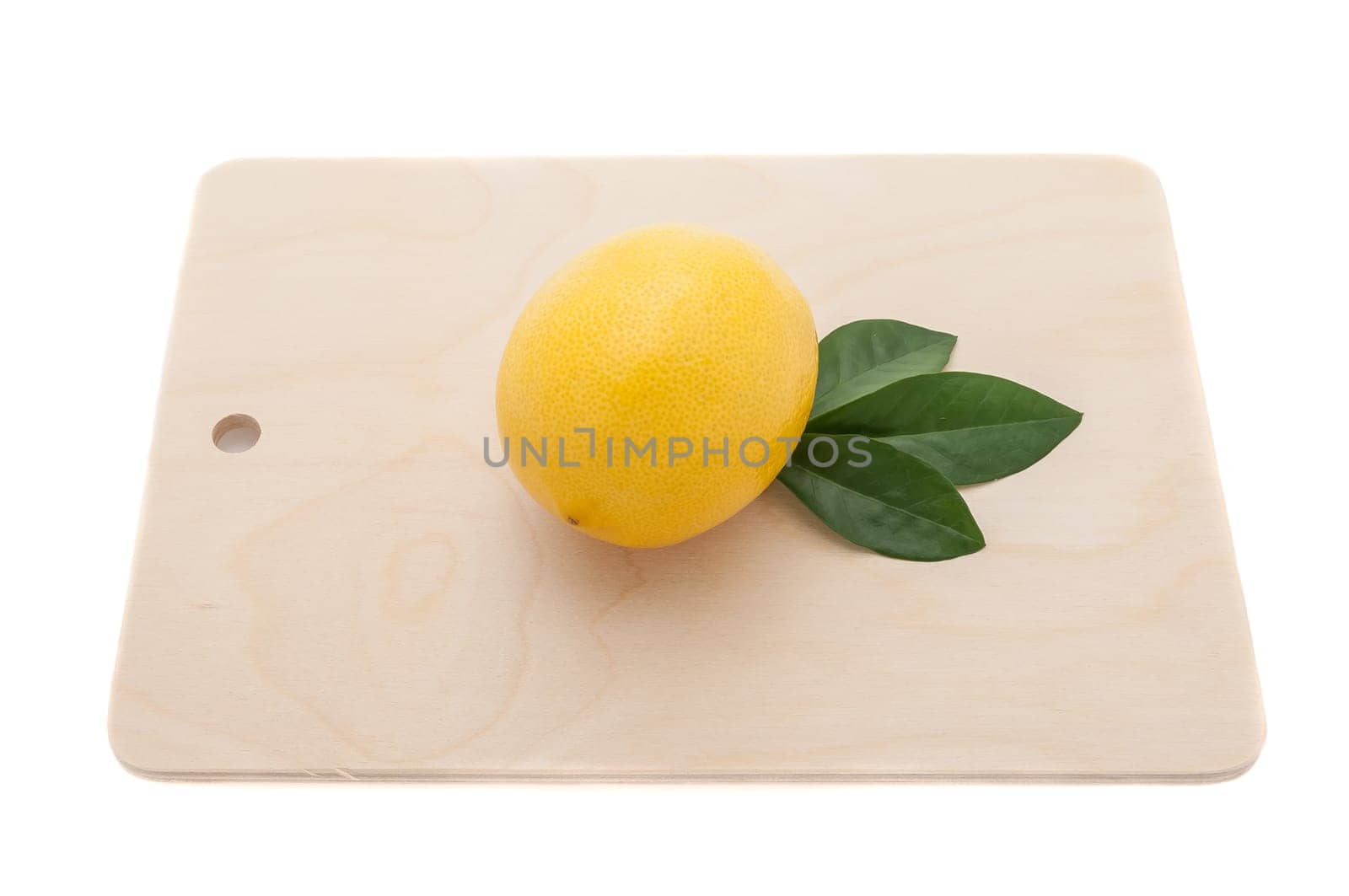 yellow lemon with three green leaves on a chopping board