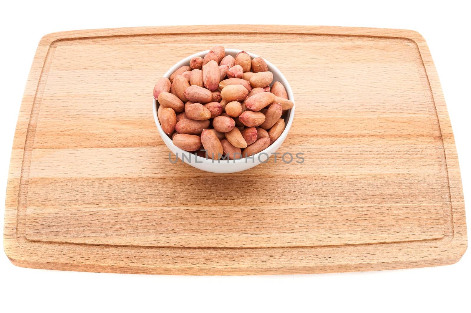 Mixed nuts in a metal brown bowl on a white wooden cutting board.