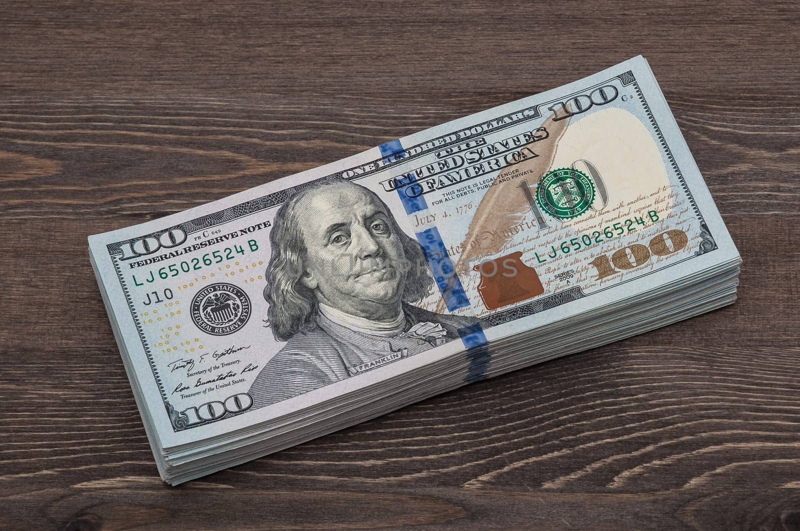 A bundle of denominations of ten thousand American dollars. against the background of a wooden table.