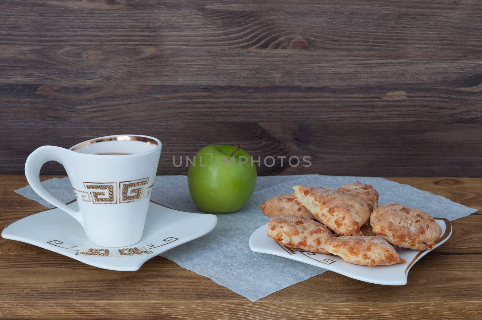A cup of tea, homemade cookies and an apple on a background of boards.