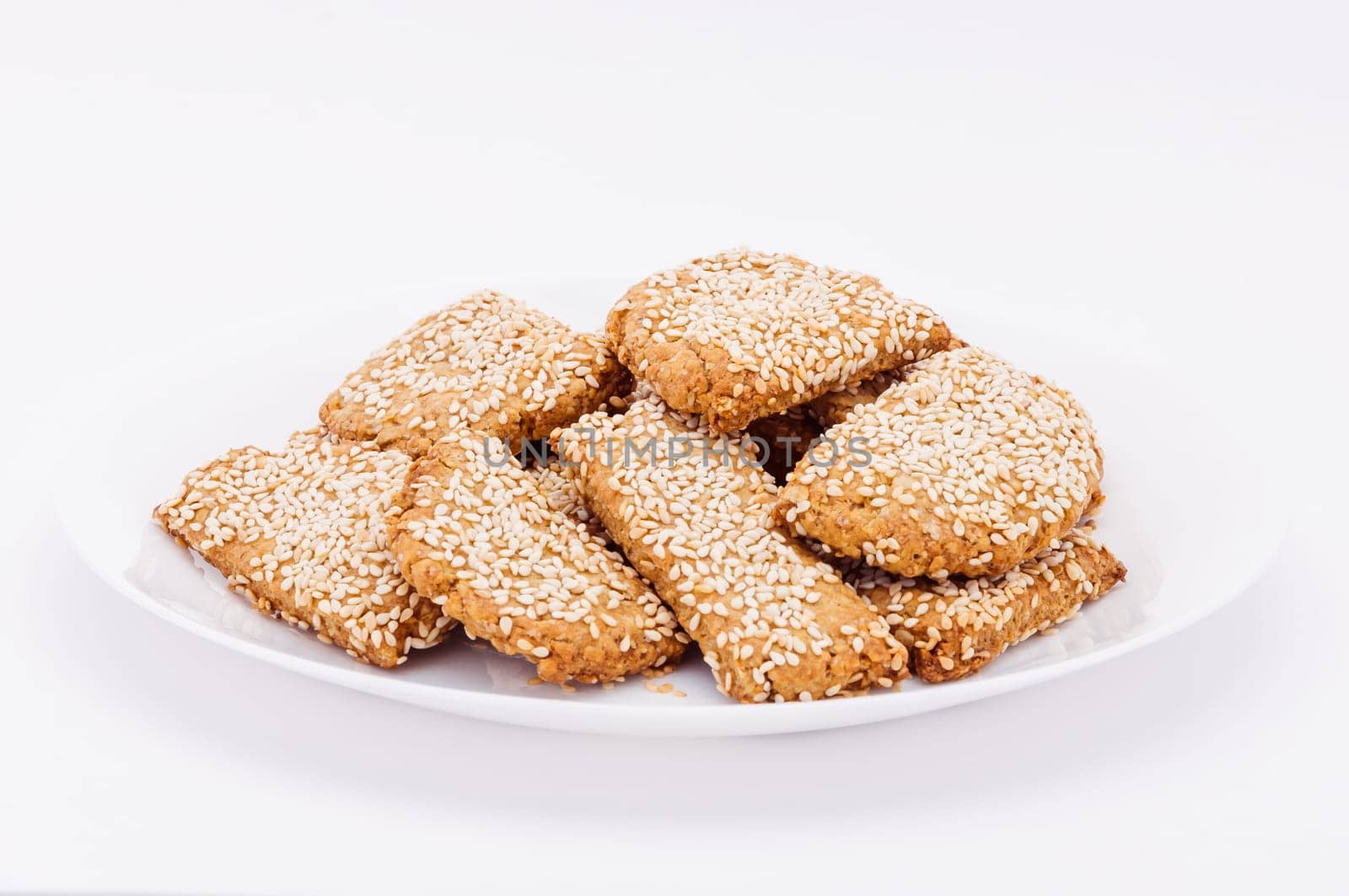 On a white plate, on a white background biscuits to sesame.