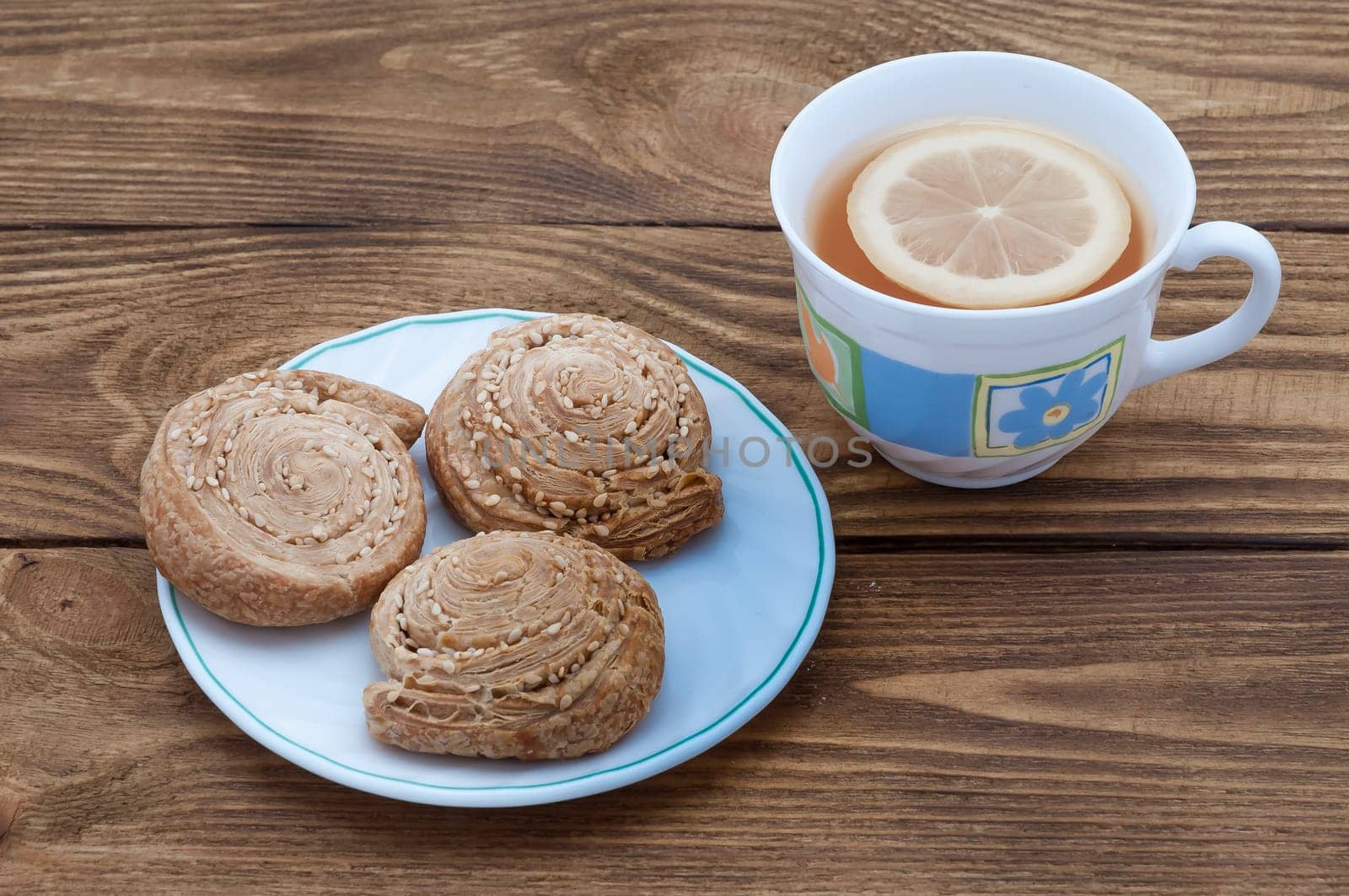A cup of fragrant tea with lemon and biscuits with sesame.