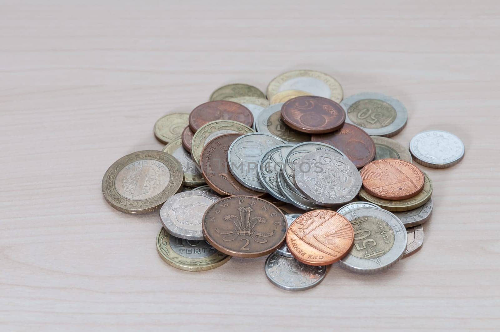 A handful of coins of different countries, dignity and size are scattered on the table.