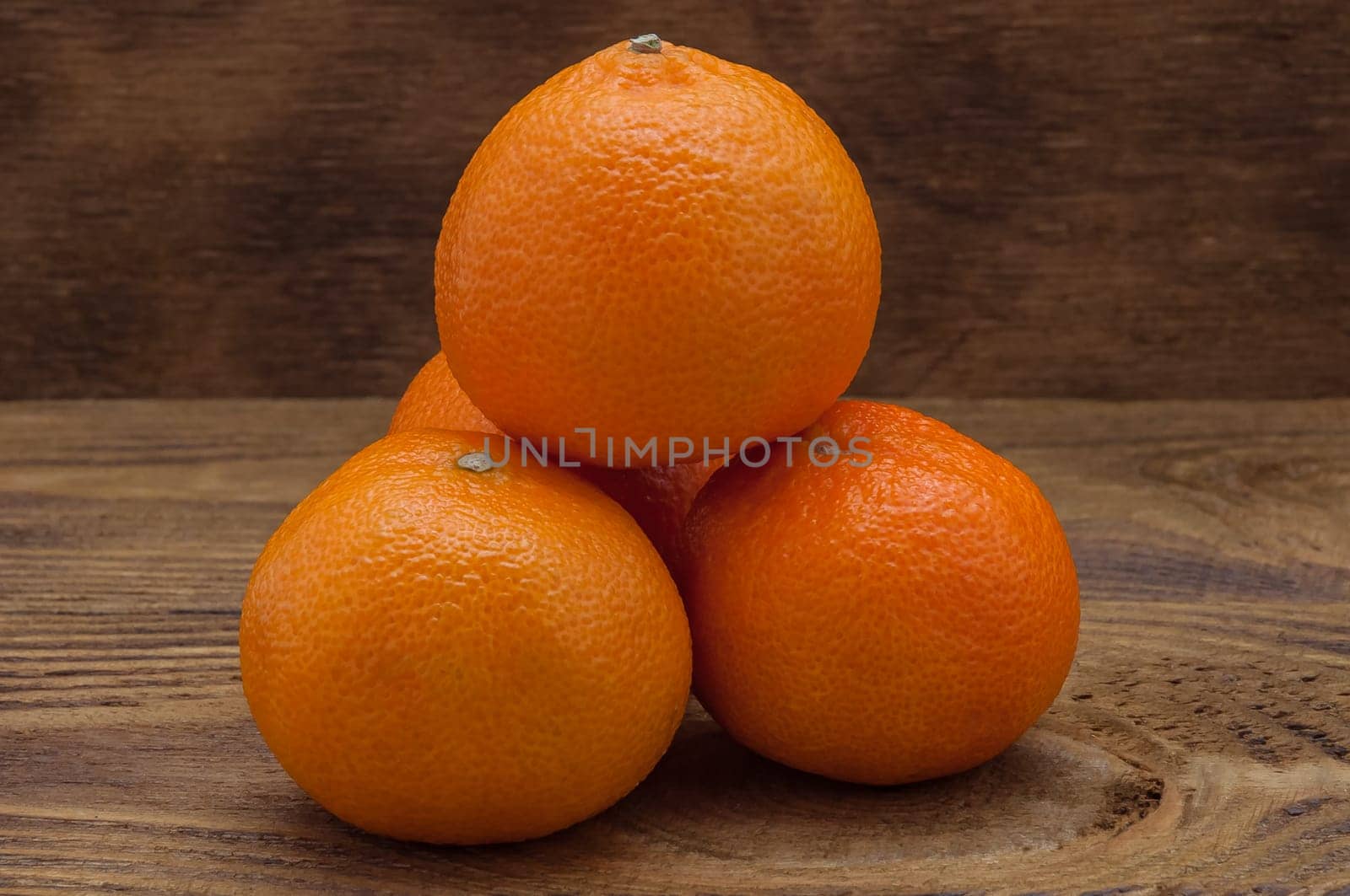 Four bright orange ripe mandarines laying a slide on a table.