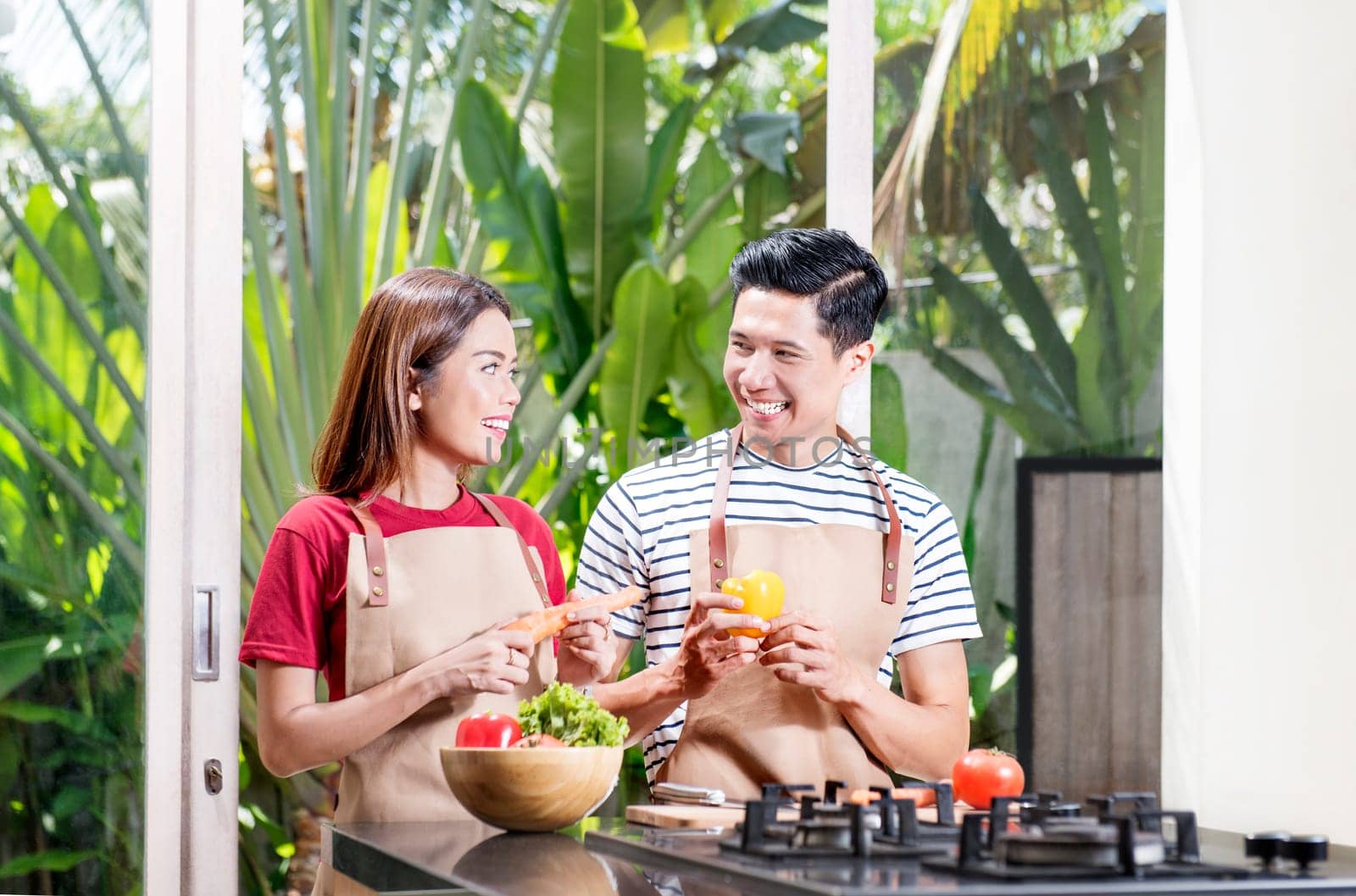 Happy asian couple preparing fresh vegetables for cooking on kitchen