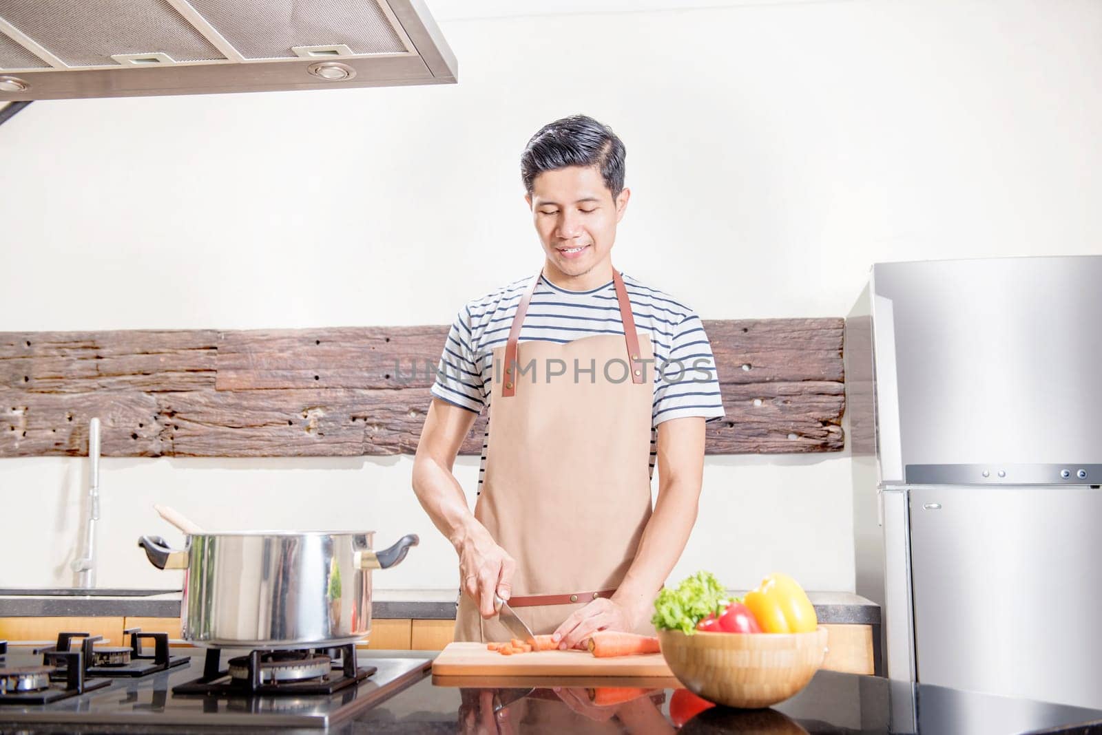 Handsome asian man slice the carrot for cooking on the kitchen