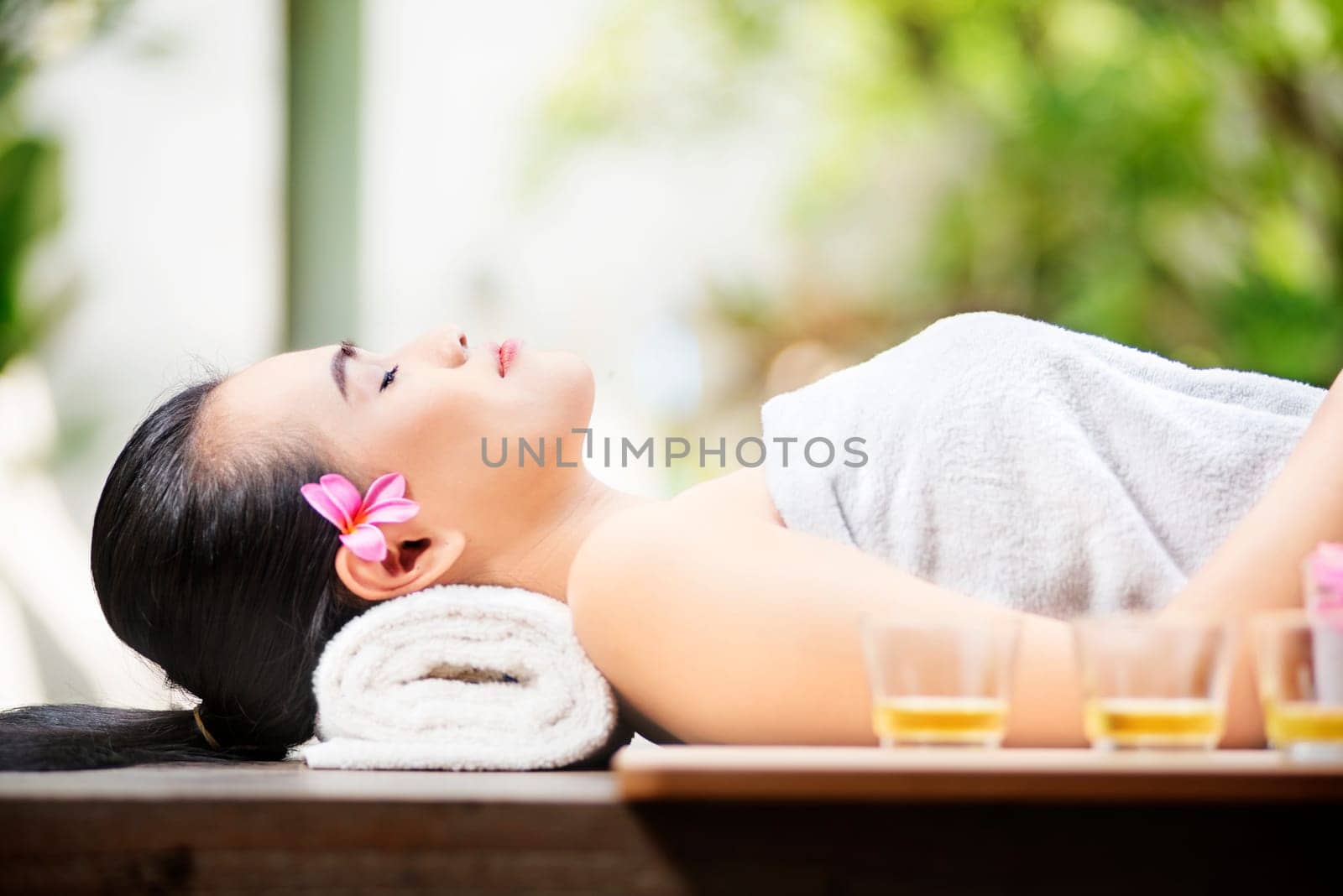 Happy asian woman lying on massage table on spa salon