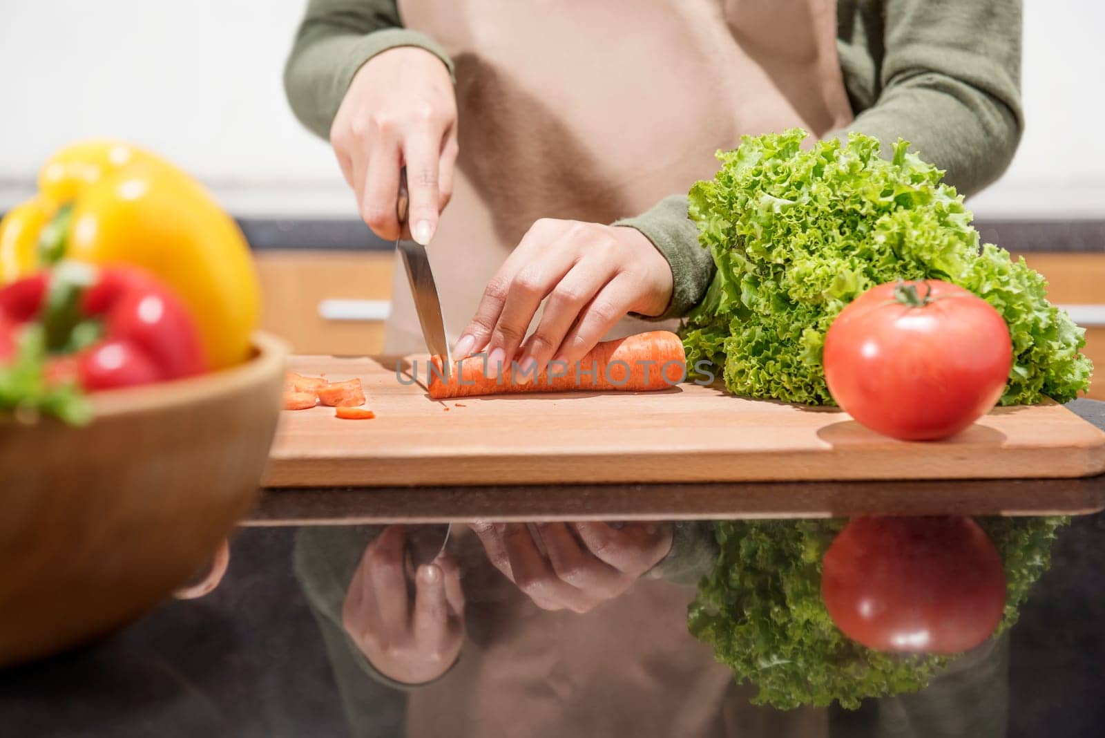 Close up view of woman hand cutting vegetables with knife on the kitchen