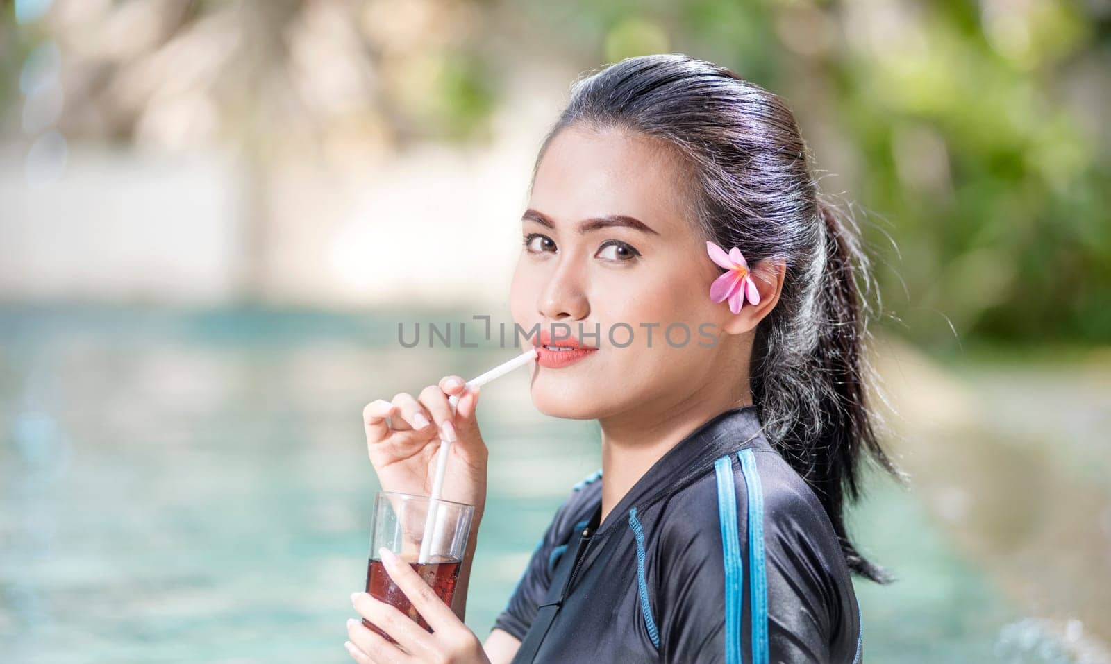 Pretty asian woman drinking cocktail on the swimming pool