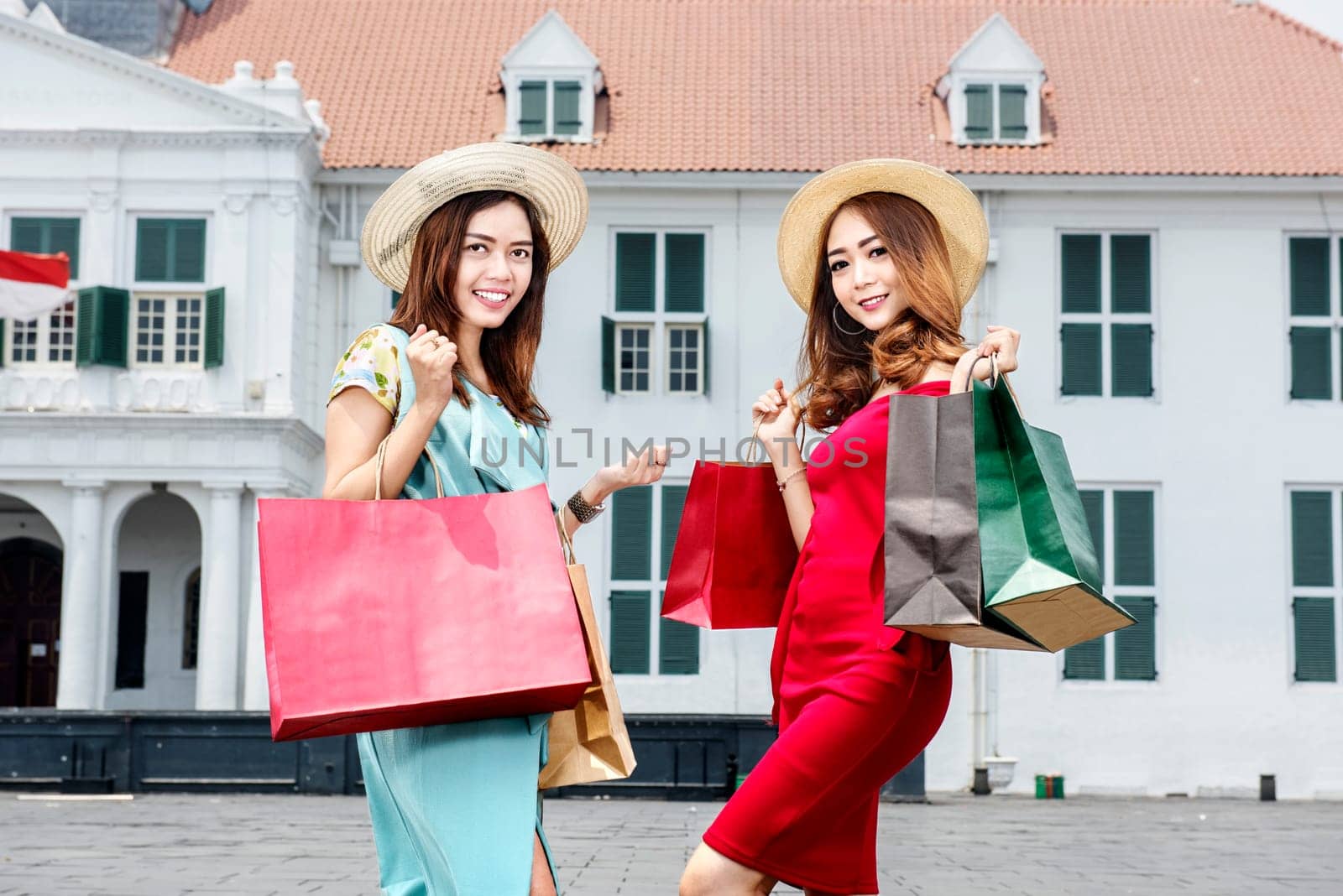 Young two asian woman with hat holding many shopping bags on the city