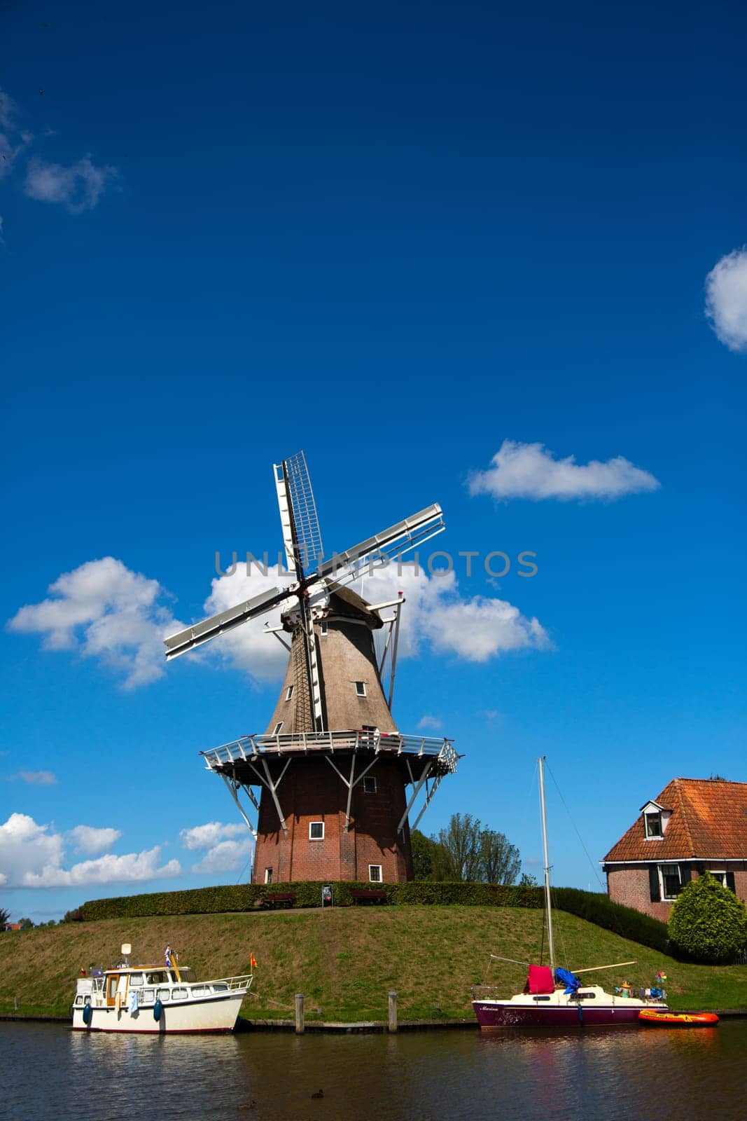 Dokkum, Friesland, The Netherlands - August 17, 2018  Boats on canal and windmill on fortifications of historic town Dokkum, Friesland, The Netherlands.