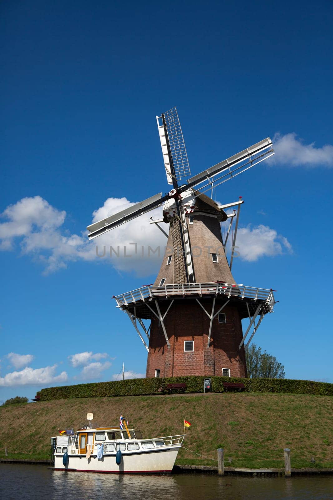 Dokkum, Friesland, The Netherlands - August 17, 2018  Boats on canal and windmill on fortifications of historic town Dokkum, Friesland, The Netherlands.