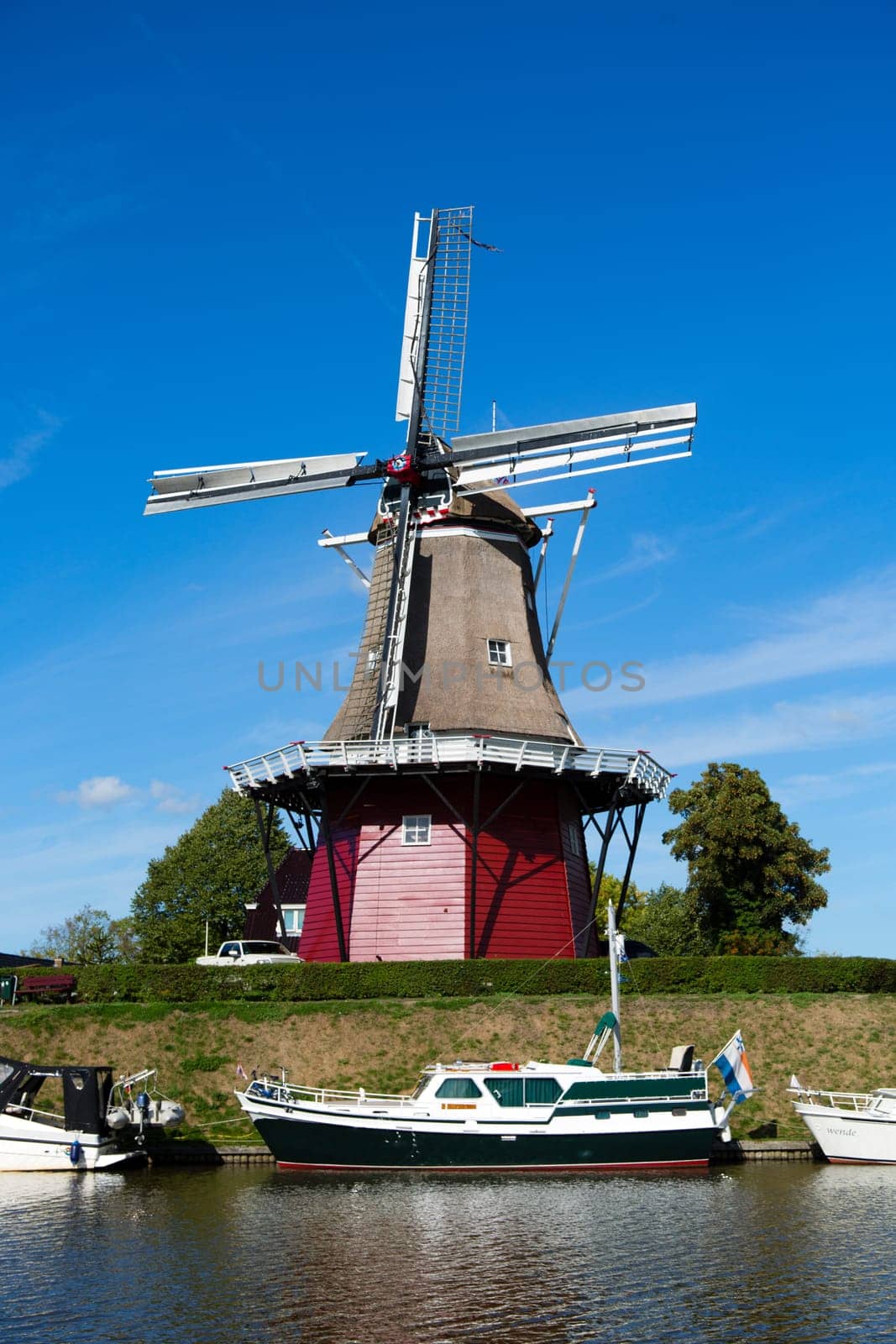 Dokkum, Friesland, The Netherlands - August 17, 2018  Boats on canal and windmill on fortifications of historic town Dokkum, Friesland, The Netherlands.