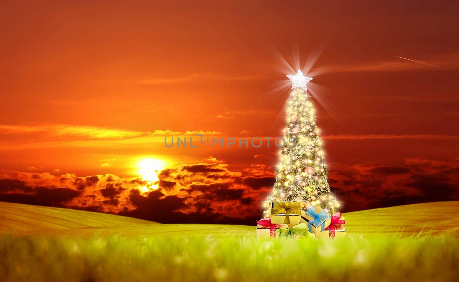 Conceptual decorated shiny Christmas tree on green landscape over cloudy red sunset sky