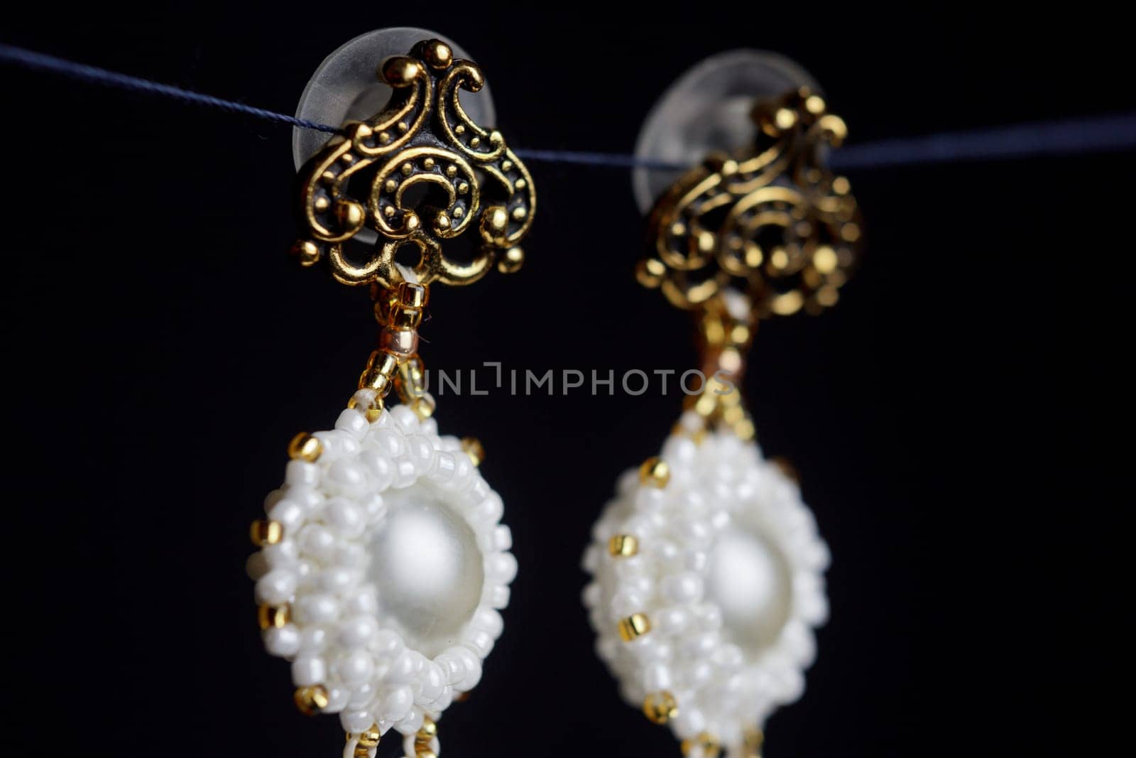 handmade jewelry made of beads in macro. earrings from white beads. earrings from stones. beautiful ornaments. earrings from red beads. ornaments on a black background