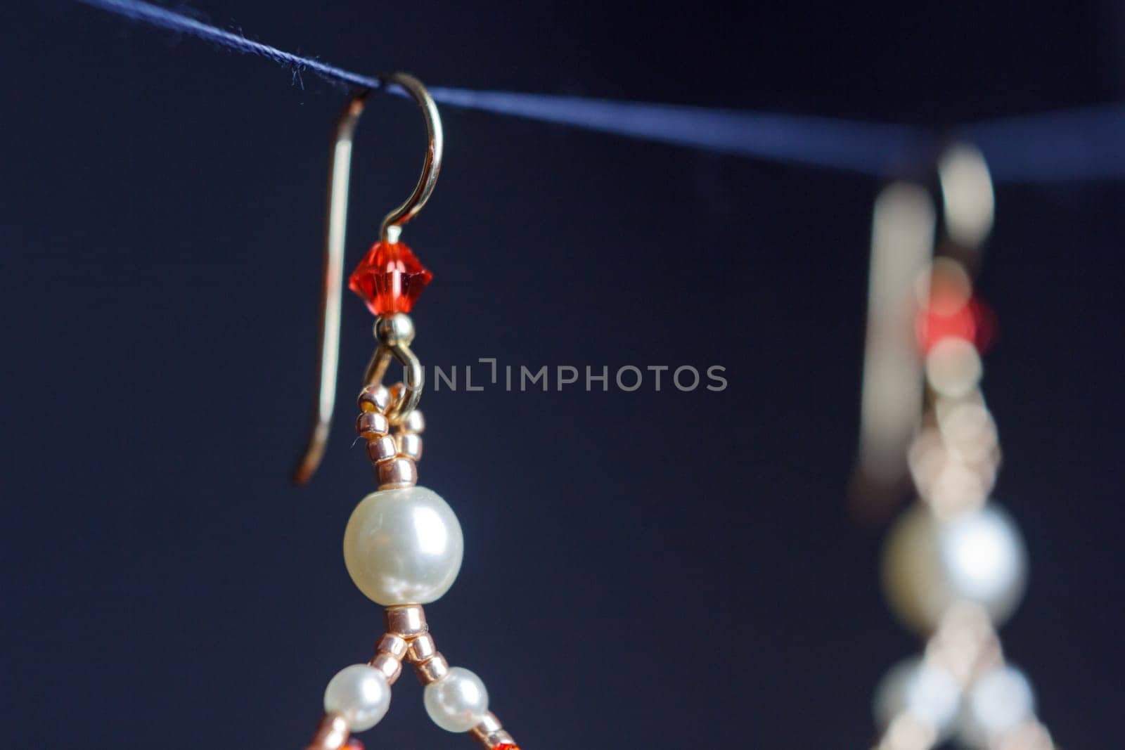 handmade jewelry made of beads in macro. earrings from white beads. earrings from stones. beautiful ornaments. earrings from red beads. ornaments on a black background