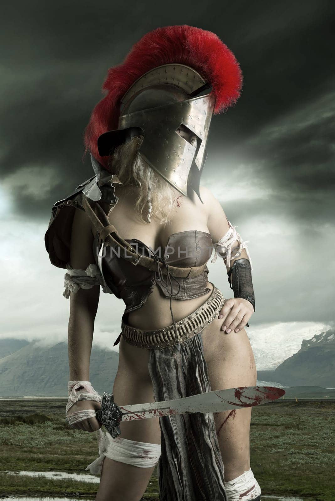 Ancient woman warrior or Gladiator posing outdoors with sword and helmet