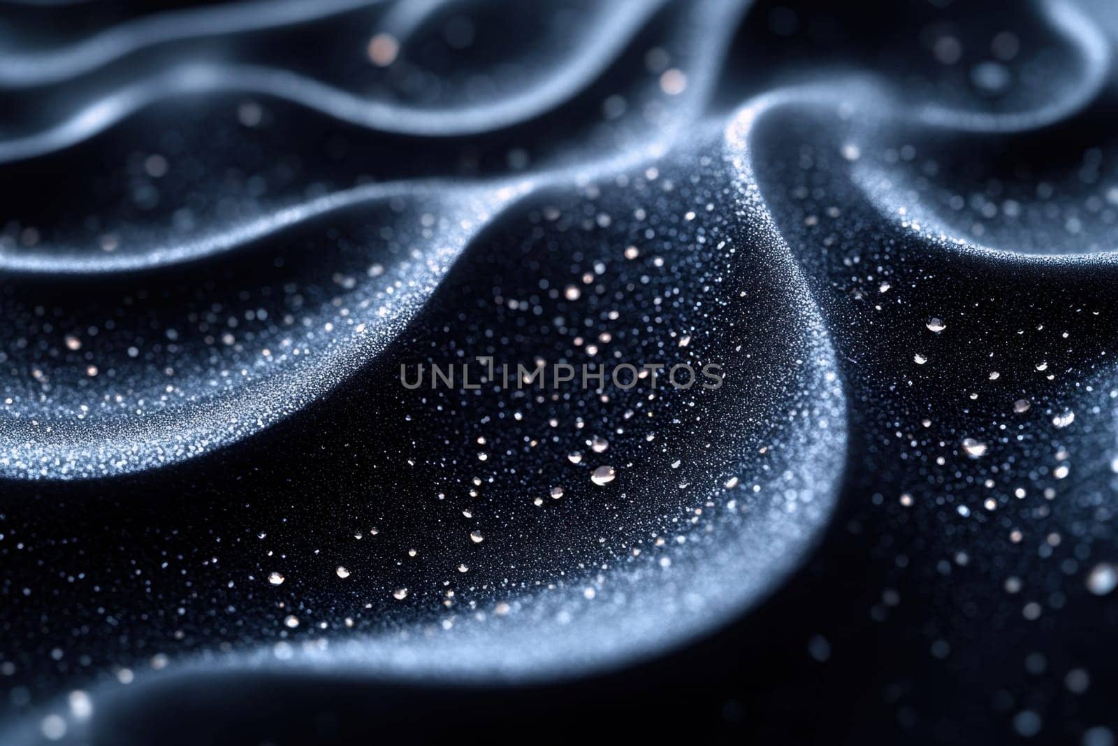 Delicate droplets of water rest on a sleek, dark material, reflecting soft light and forming enchanting wave-like patterns. The scene captures the intricate beauty of nature and design in a harmonious blend of textures.