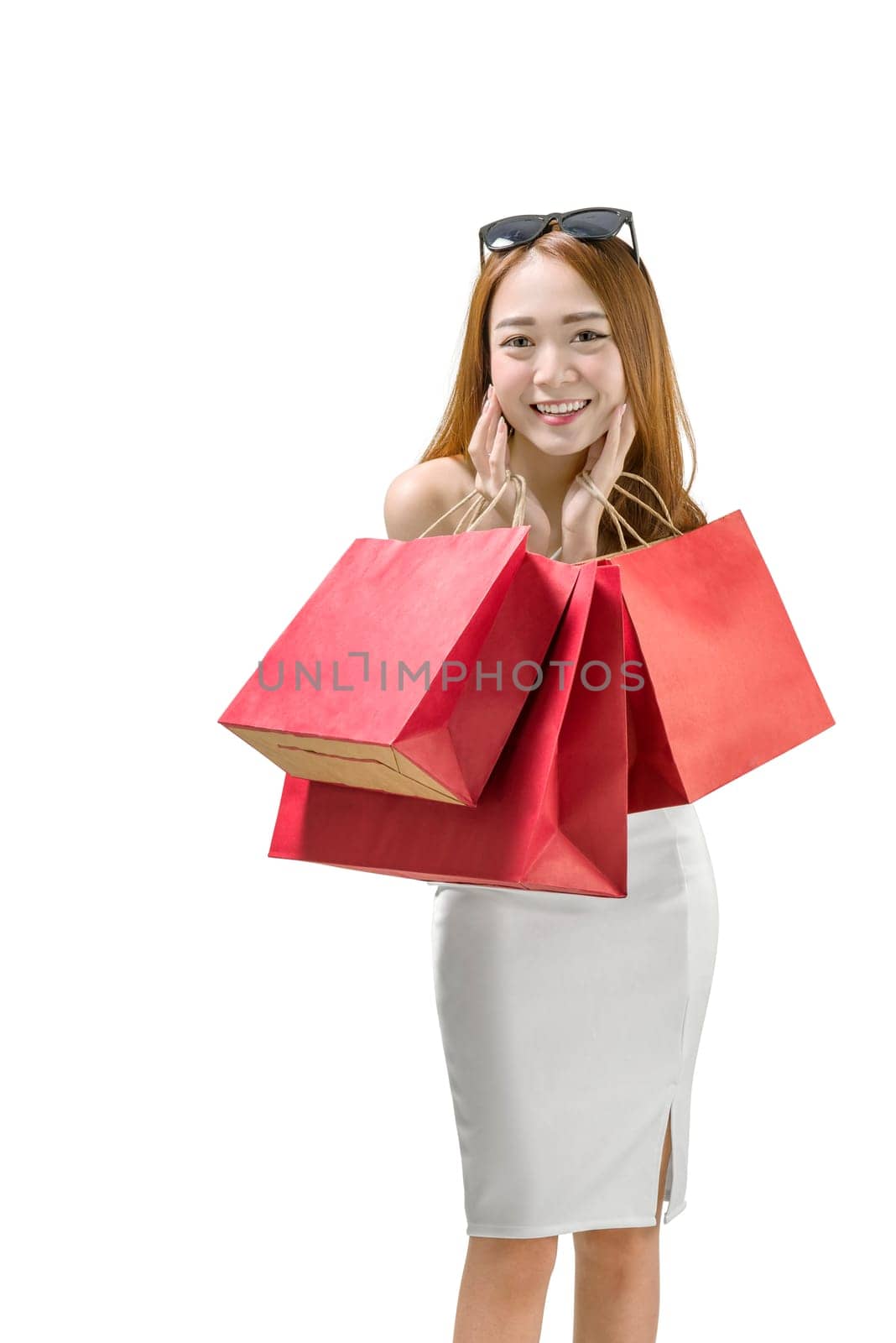 Smiling asian luxury woman with many red shopping bags posing isolated over white background