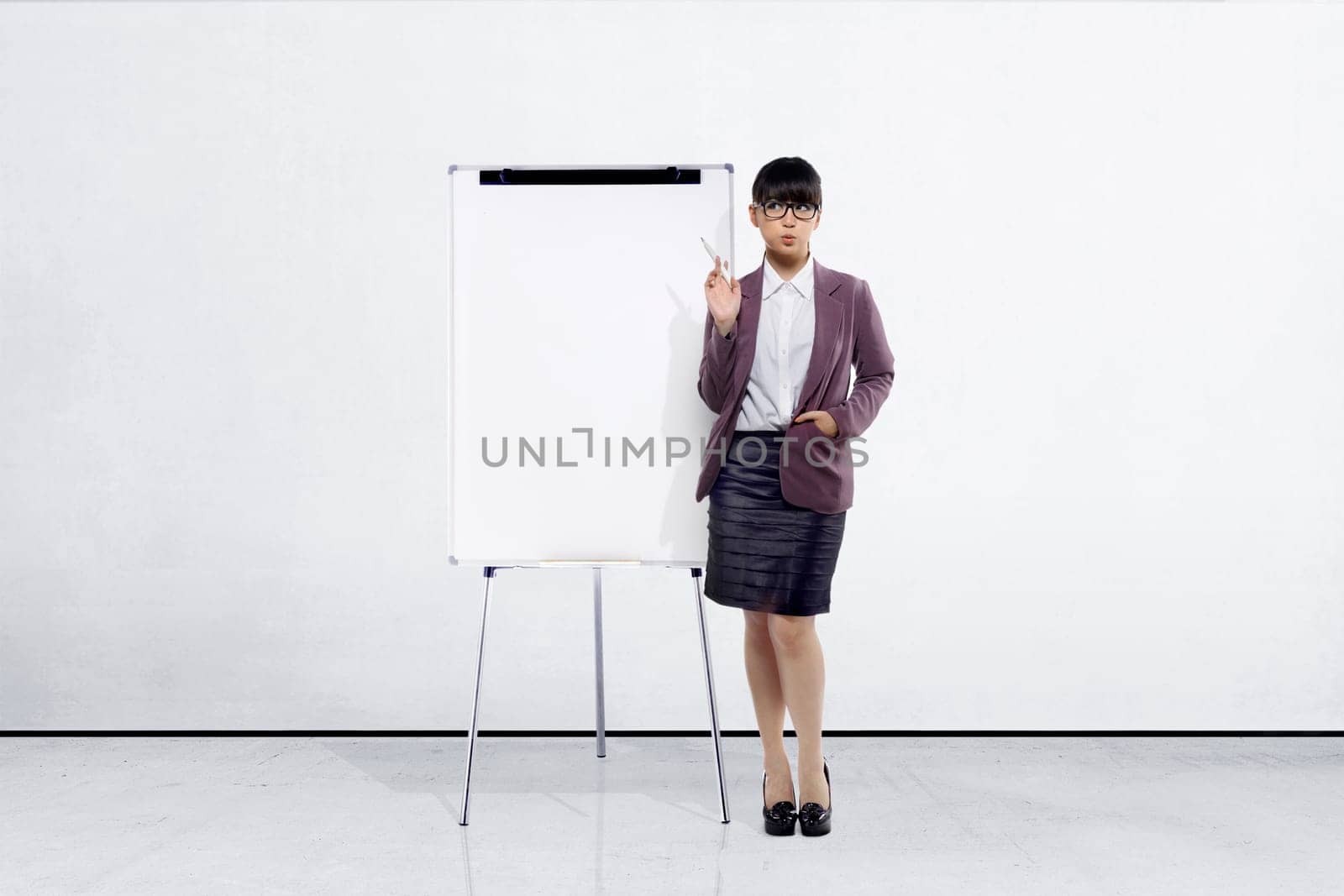 Young asian businesswoman with marker pen standing beside whiteboard in office room
