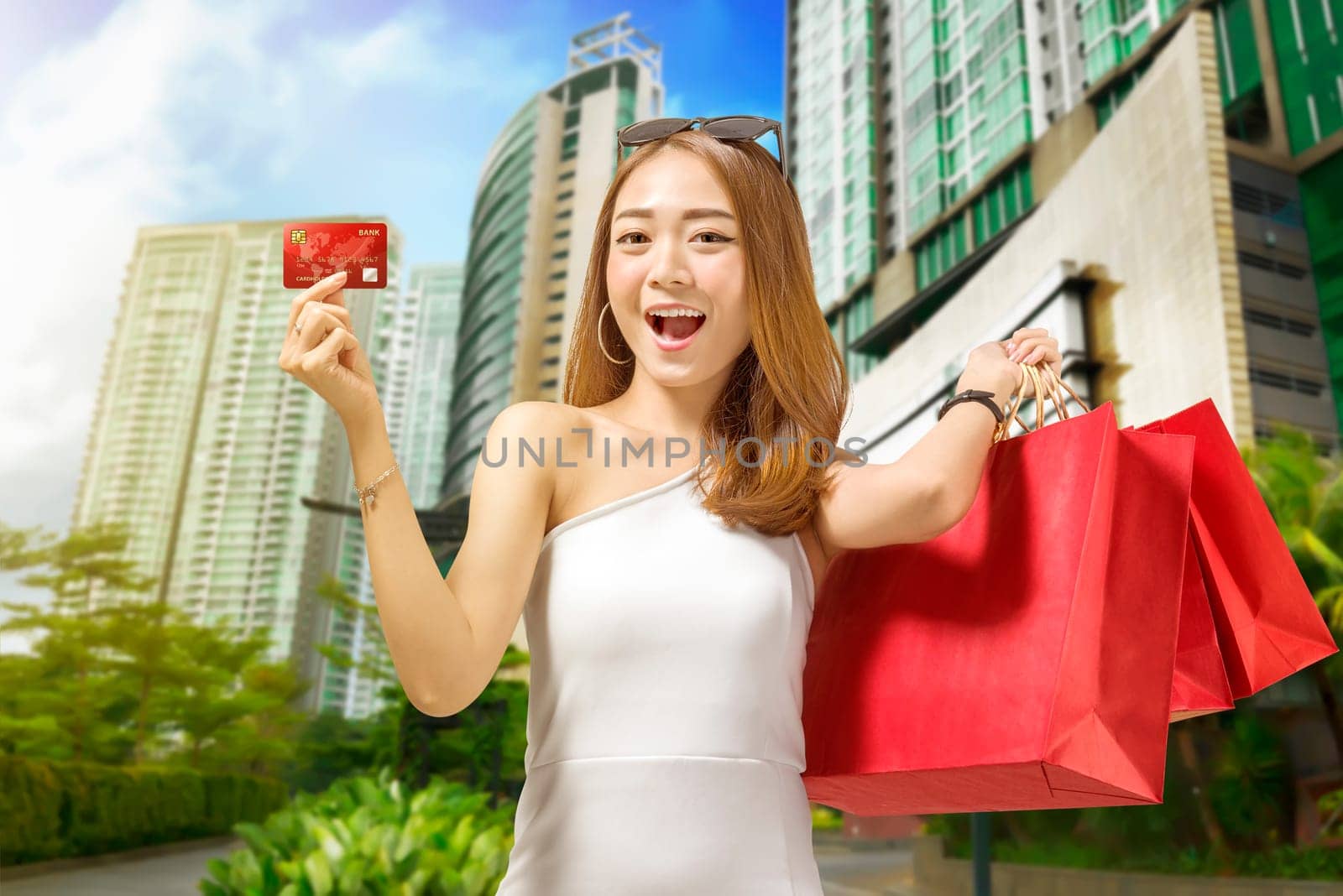 Young asian woman holding shopping bags and credit card outside the mall