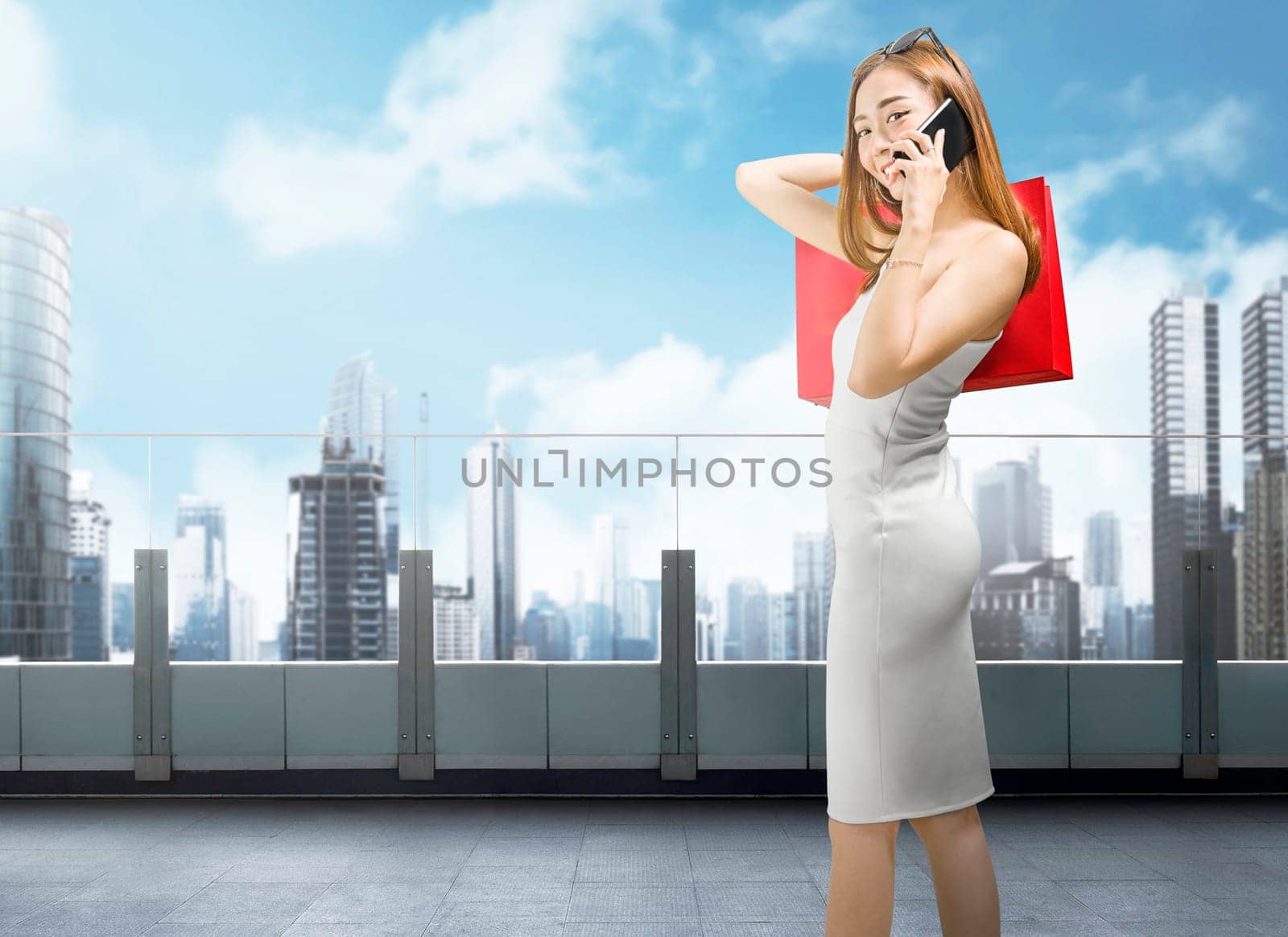 Beautiful asian woman with smartphone and red shopping bags on mall balcony