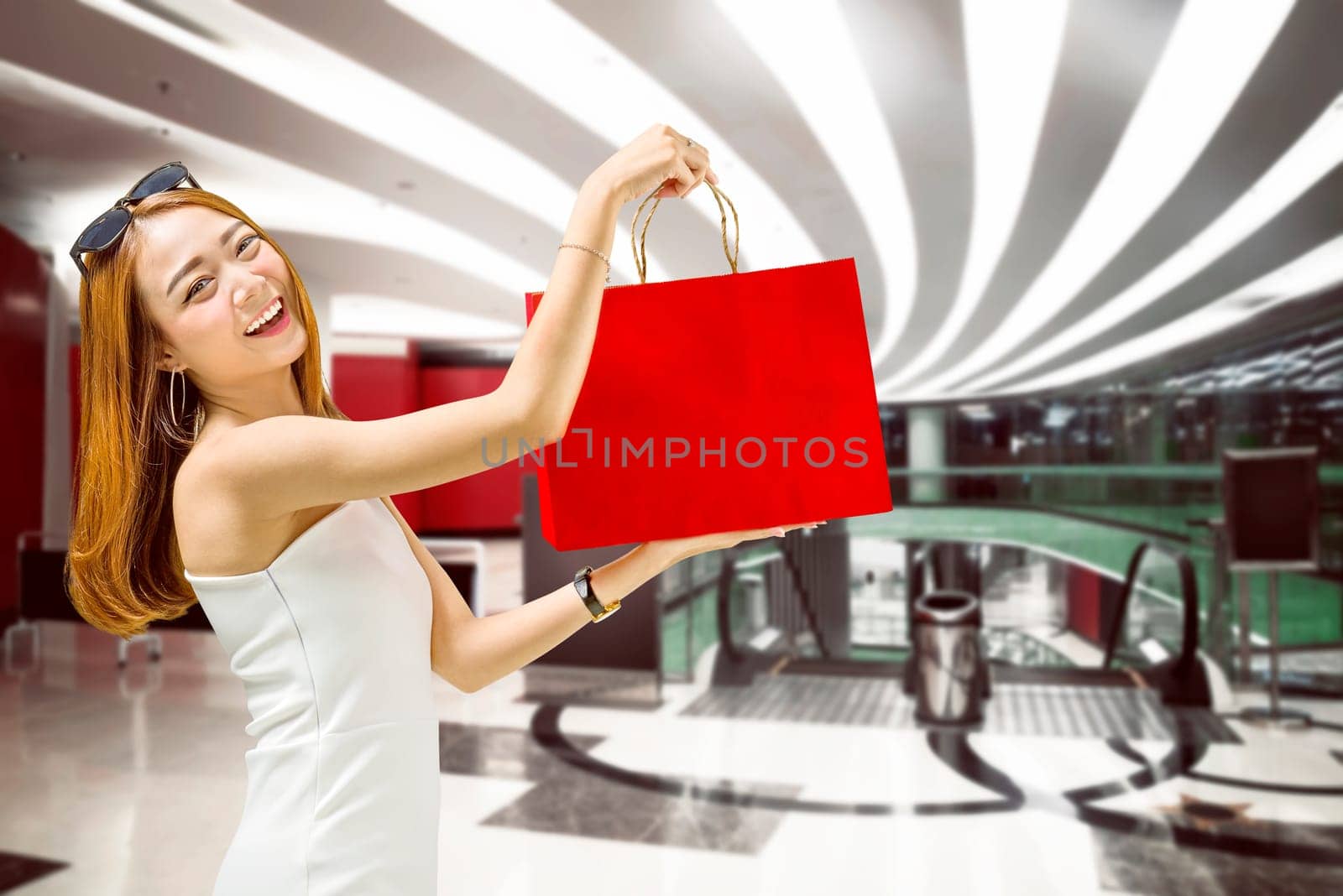 Beautiful asian woman showing her shopping bags in mall. Black friday concept