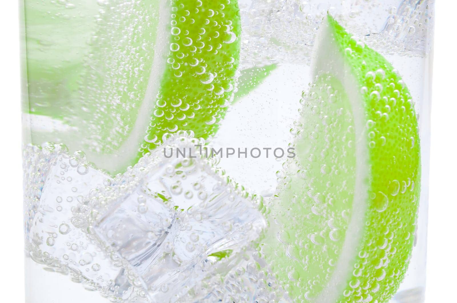 Pieces of fresh juicy lime sink into crystal clear water.